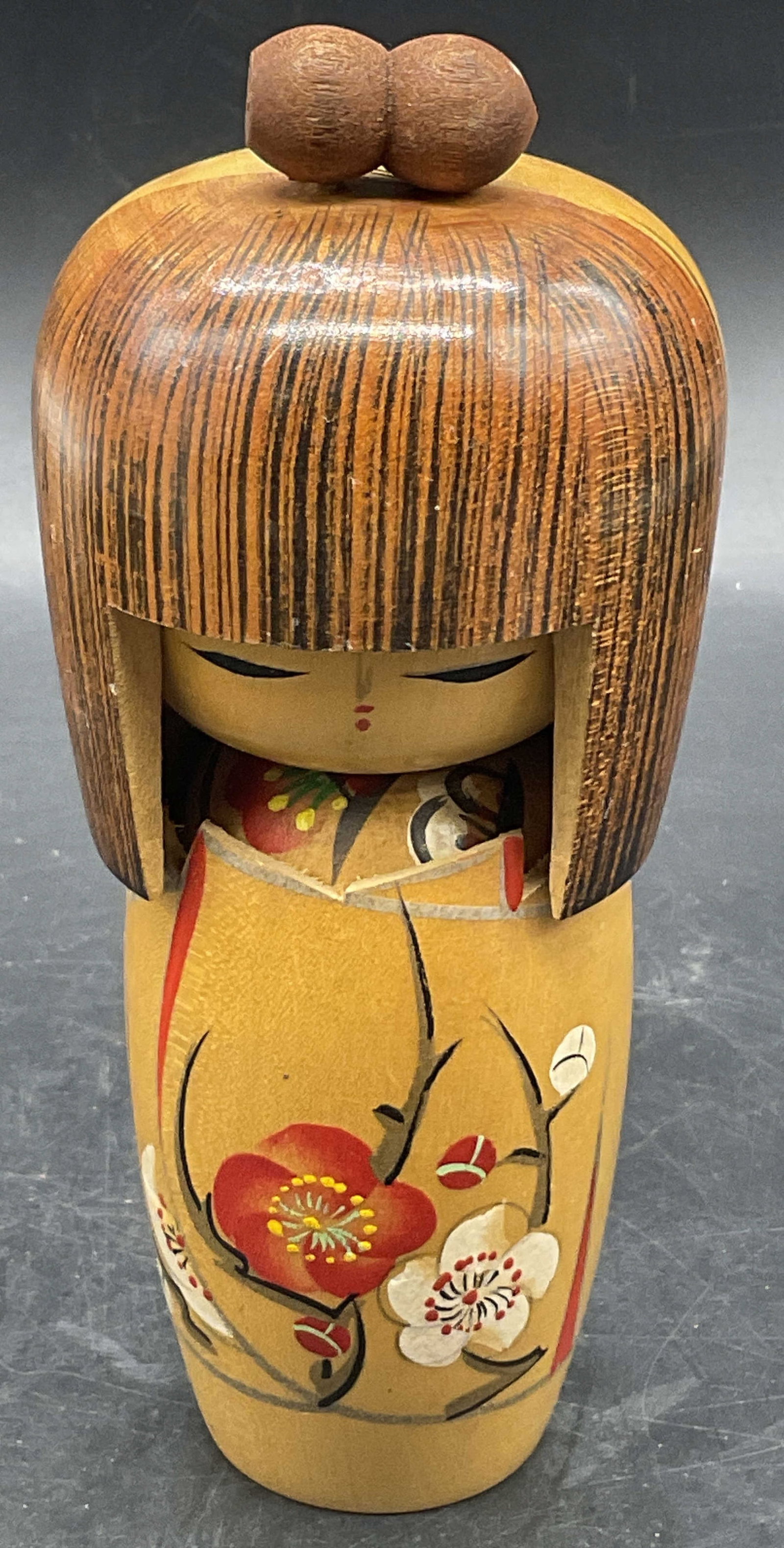 Vintage Asian Wooden Kokeshi Doll: Vintage Asian Wooden Kokeshi Doll. Hand painted details to the doll. Primarily brown, red, white, yellow, black, and teal hues. Measures approx. 6.25H x 2.25W in. Surface wear and chipping present. Po