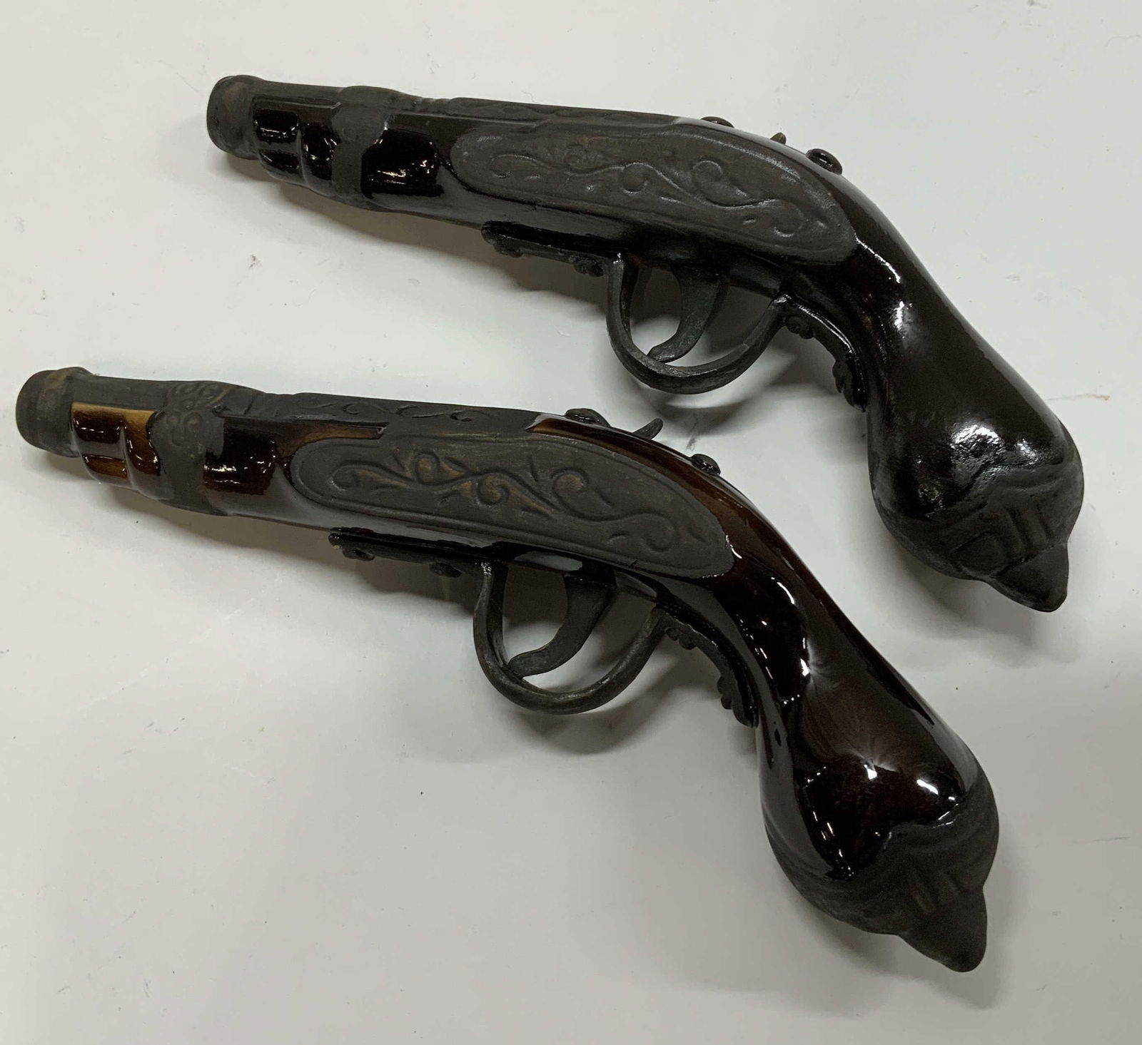 Pr Vintage Liquor Bottle Decanter Pistol Gun: Vintage Liquor Bottle Decanter Pistol Gun. 2 ceramic decanters, it has a detailed resemblance as a pistol gun. Has dark brown & grey colors with a stem like engraving on the pistol gun. The ceramic pi