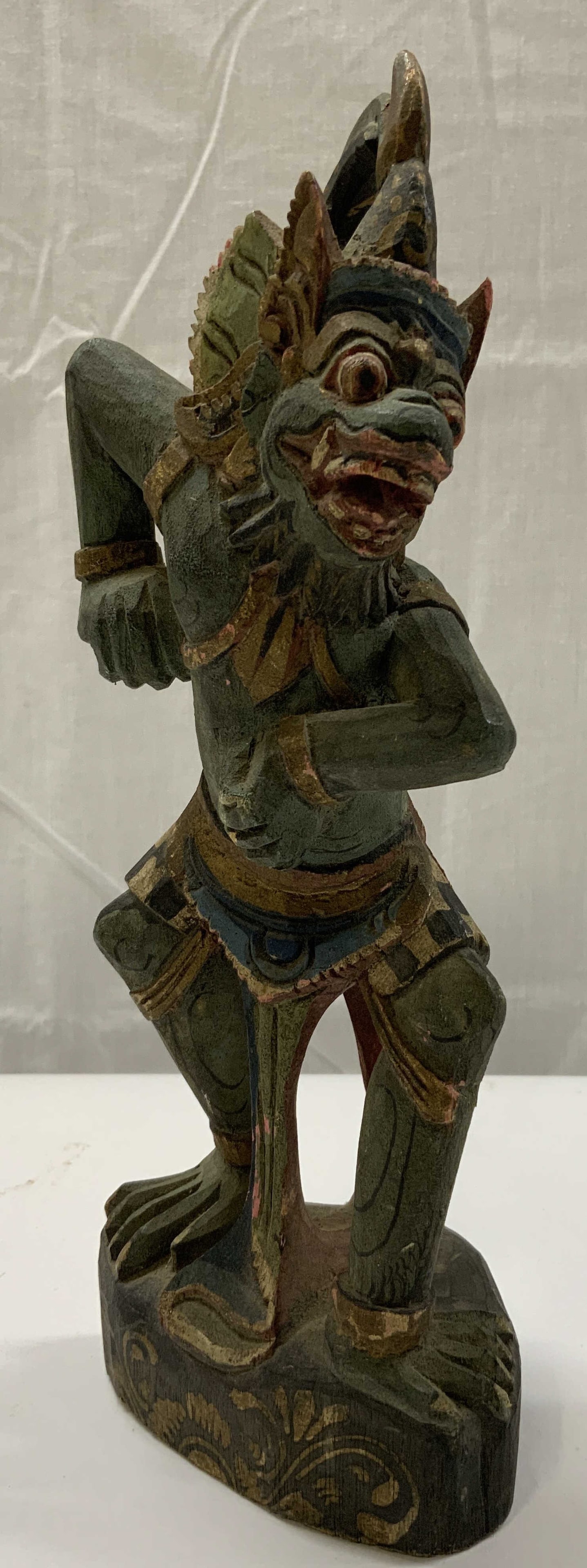 Antique Hand Carved Balinese Figural Indonesia: Antique Hand Carved Balinese Figural. Wood Balinese figural, it has extensive detail and a unique face. It has a green color with a long tail. The figural arms are in a distinctive pose. Hand MADE IN 