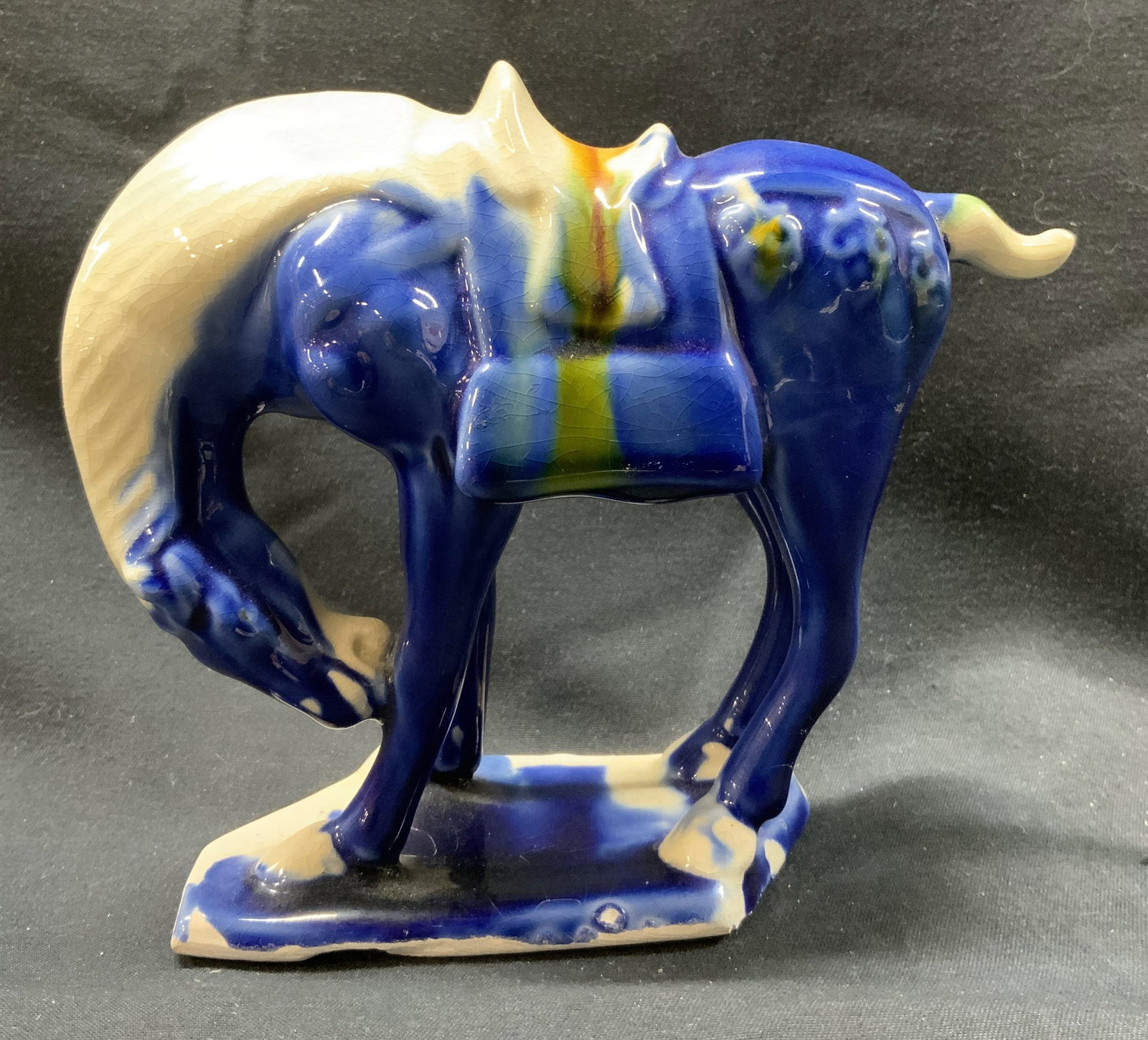 Vintage Porcelain Majolica Horse Figurine: Vintage Porcelain Majolica Horse Figurine. Blue majolica horse figurine which is wearing a white saddle. Horse is standing up with its head looking down. Figurine is standing on a blue base. Very dist