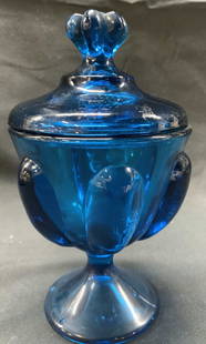 Cobalt Blue Glass Covered Urn: Cobalt Blue Glass Covered Urn. Clear glossy glass urn, has a decorative lid. Has a raised pedestal base. Surface wear consistent with age, use & exposure. No visible signature. Measurements: length 3.