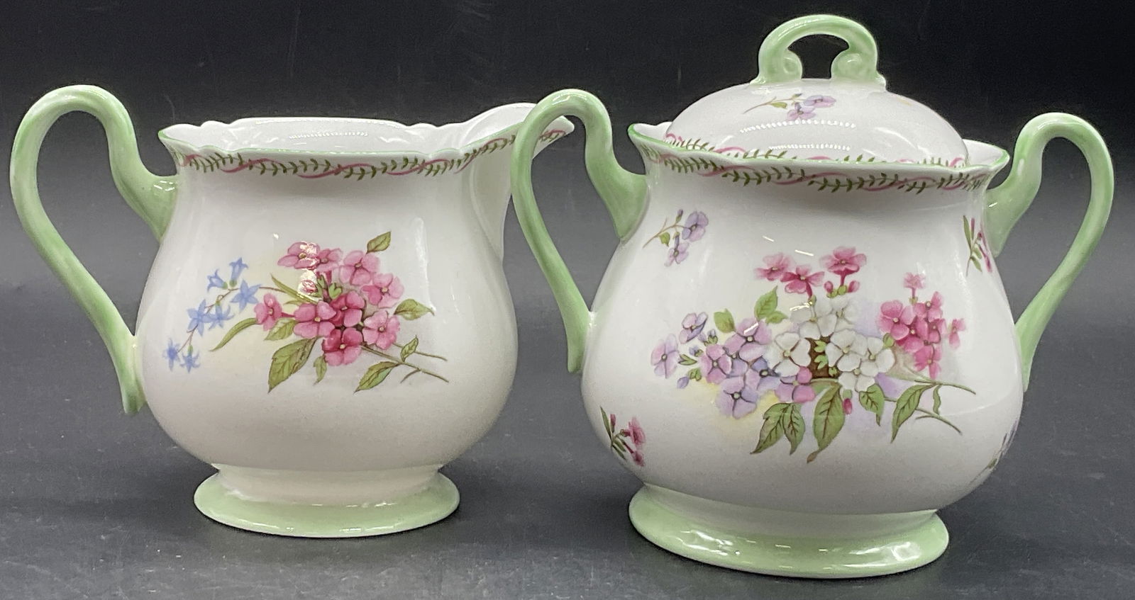 SHELLEY ENGLAND BONE CHINA Sugar Bowl & Creamer: SHELLEY ENGLAND FINE BONE CHINA Lidded Sugar Bowl & Creamer. Underside reads FINE BONE CHINA, SHELLEY, ENGLAND. The creamer measures approx. 4H x 5W in. Measured at widest point. Surface wear and disc