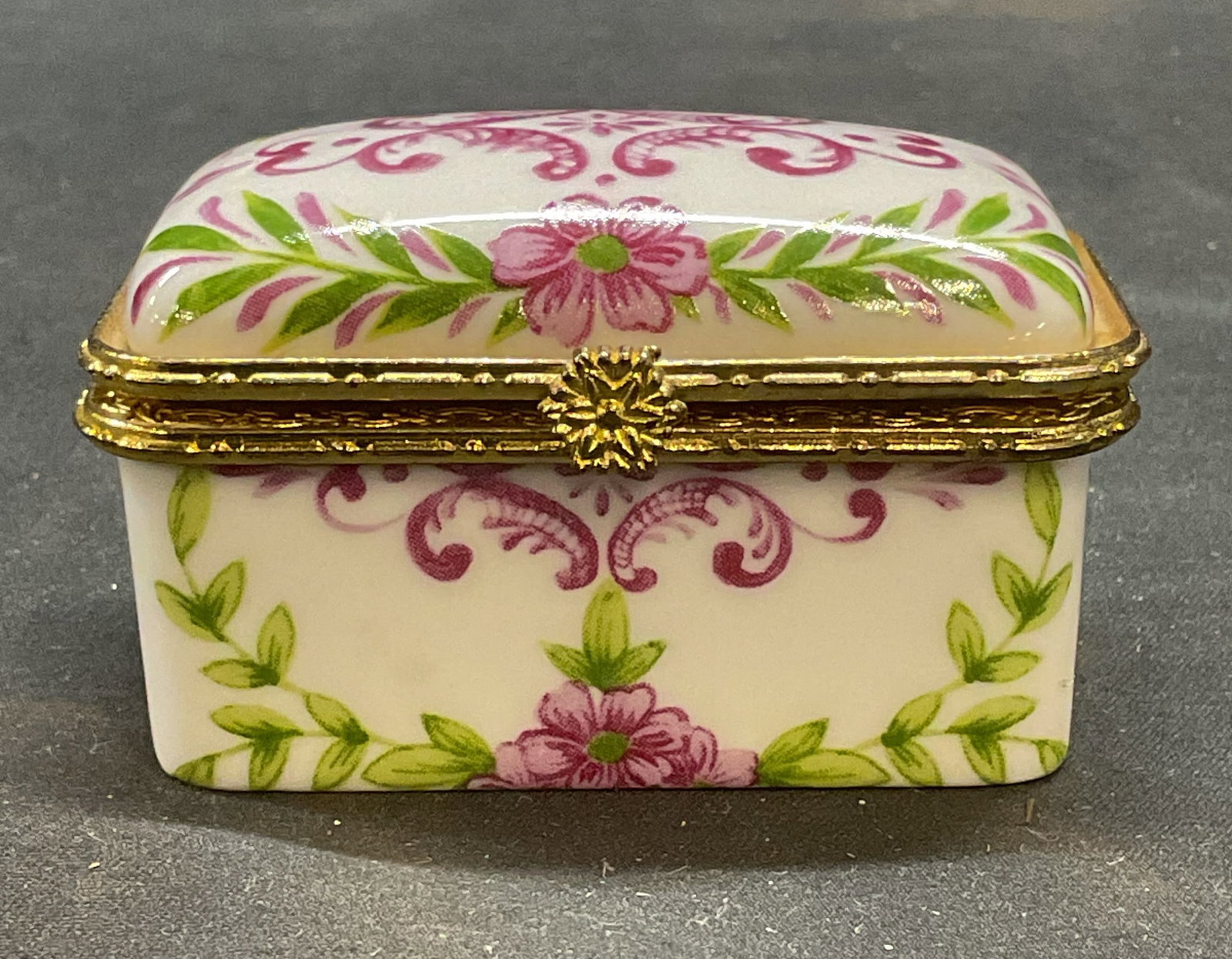 Vintage Porcelain Floral Trinket Box: Vintage porcelain trinket box with floral motif in pink and green. Gold tone hinge and rim. Measures approx 2.25 x 1.5 x 1.5 inches. Some wear including scratching. Trinket box, Vintage trinket box, p