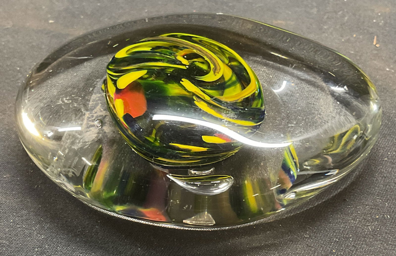 Hand Blown Yellow Swirl Art Glass Paperweight: Hand blown art glass paperweight with yellow, black, and red swirl encased in clear glass. Measures approx 3.25 inches wide. Some wear including scratching. Art glass, art glass paperweight, swirl pap