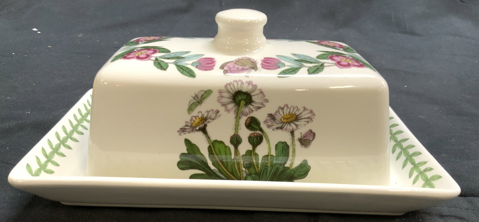 PORTMEIRION Porc Butter Dish W Lid: Underside reads PORTMEIRION THE BOTANIC GARDEN. Butter dish is porcelain. Piece include lid. Dish has multi toned floral and leaf detail. Lid has knob style handle at top. Butter dish with lid measure