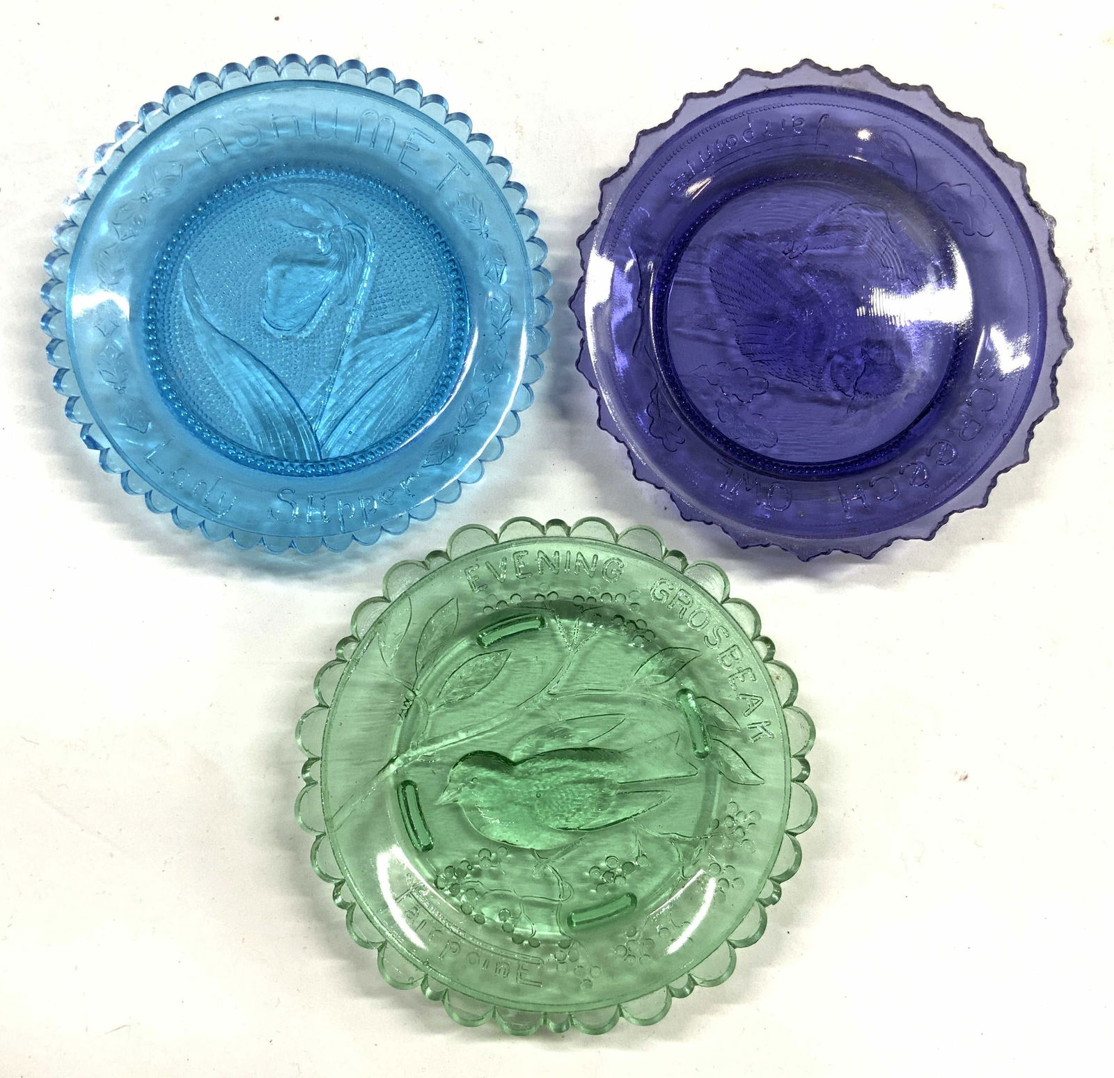 PAIRPOINT Glass Lot 3 Art Gls Trinket Dishes: Two trinket dishes are trademarked PAIRPOINT, 1 reads ASHUMET LADY SLIPPER. Each dish is glass. Lot includes 1 blue, 1 purple & 1 green toned trinket dish. Each piece has toothed rims. Trinket dishes