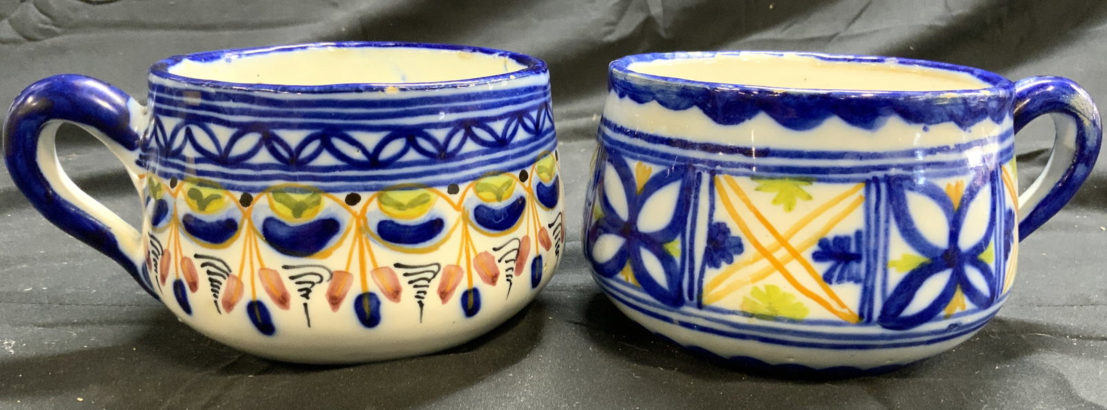 P ARZOBISPO MH Toledo 2 Ceramic H Painted Cups: Underside of one if signed P ARZOBISPO MH Toledo. The other MH. Each piece is hand painted and ceramic. Each have differing multi toned stripe, geometric & leaf detail. Each cup has half heart form ha