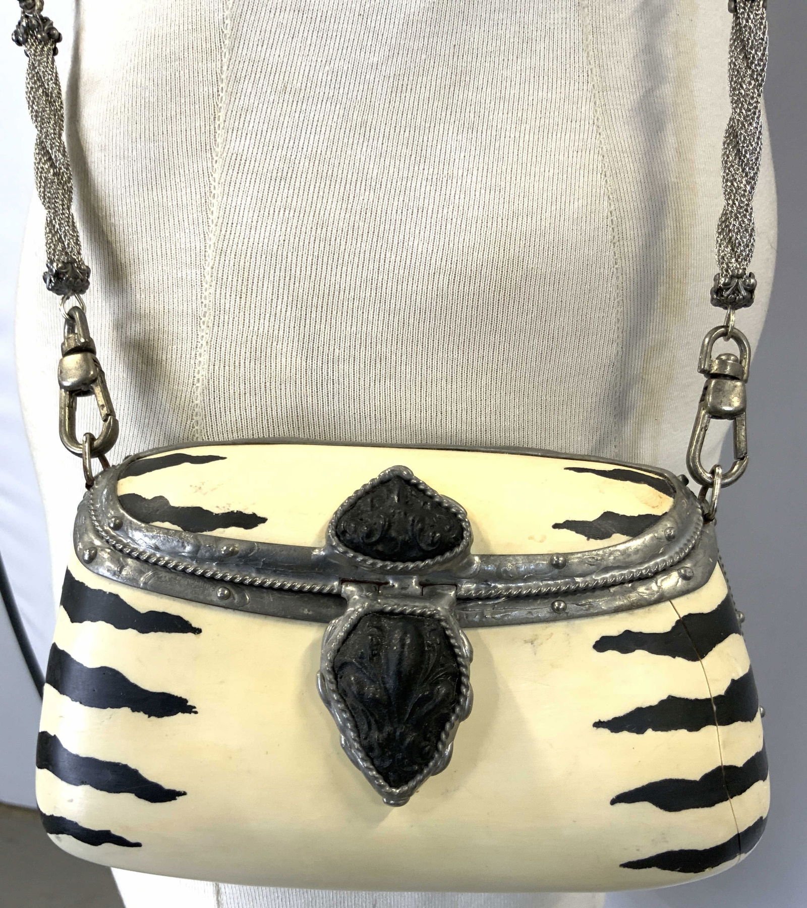 MAYA Resin Zebra Print Purse: Backside is inscribed MAYA. Purse is cream and black toned with zebra stripe print detail. Piece has braided metal strap. Purse has button clasp. Ends of straps appear to be natural stone & geometric