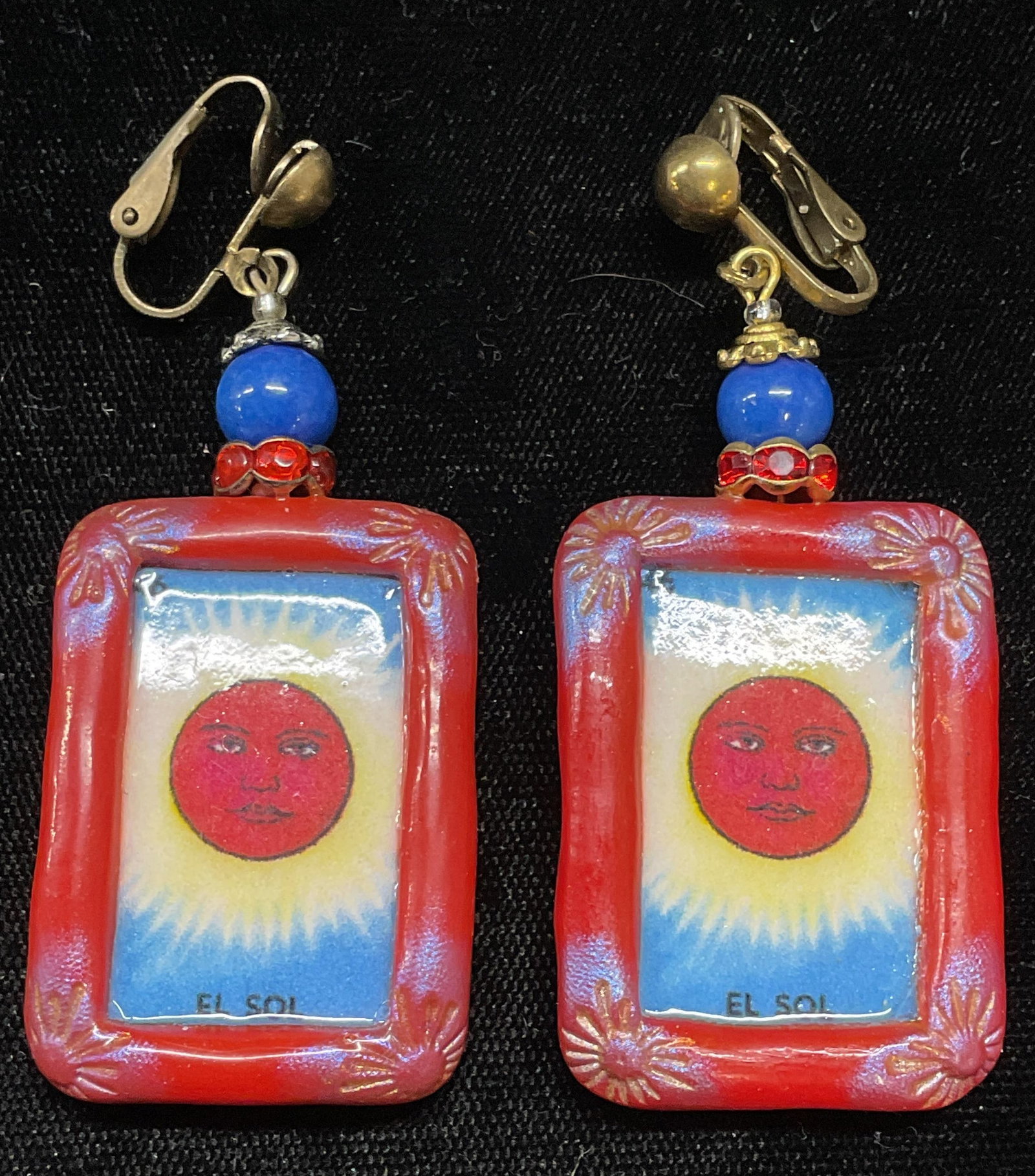 Indigo Dragon The Sun Tarot Card Earrings: Handmade The Indigo Dragon composite earrings with El Sol sun tarot card motif. Signed on underside. Measures approx 2.5 x 1 inches. Some wear including scratching observed. Jewelry, estate jewelry, c