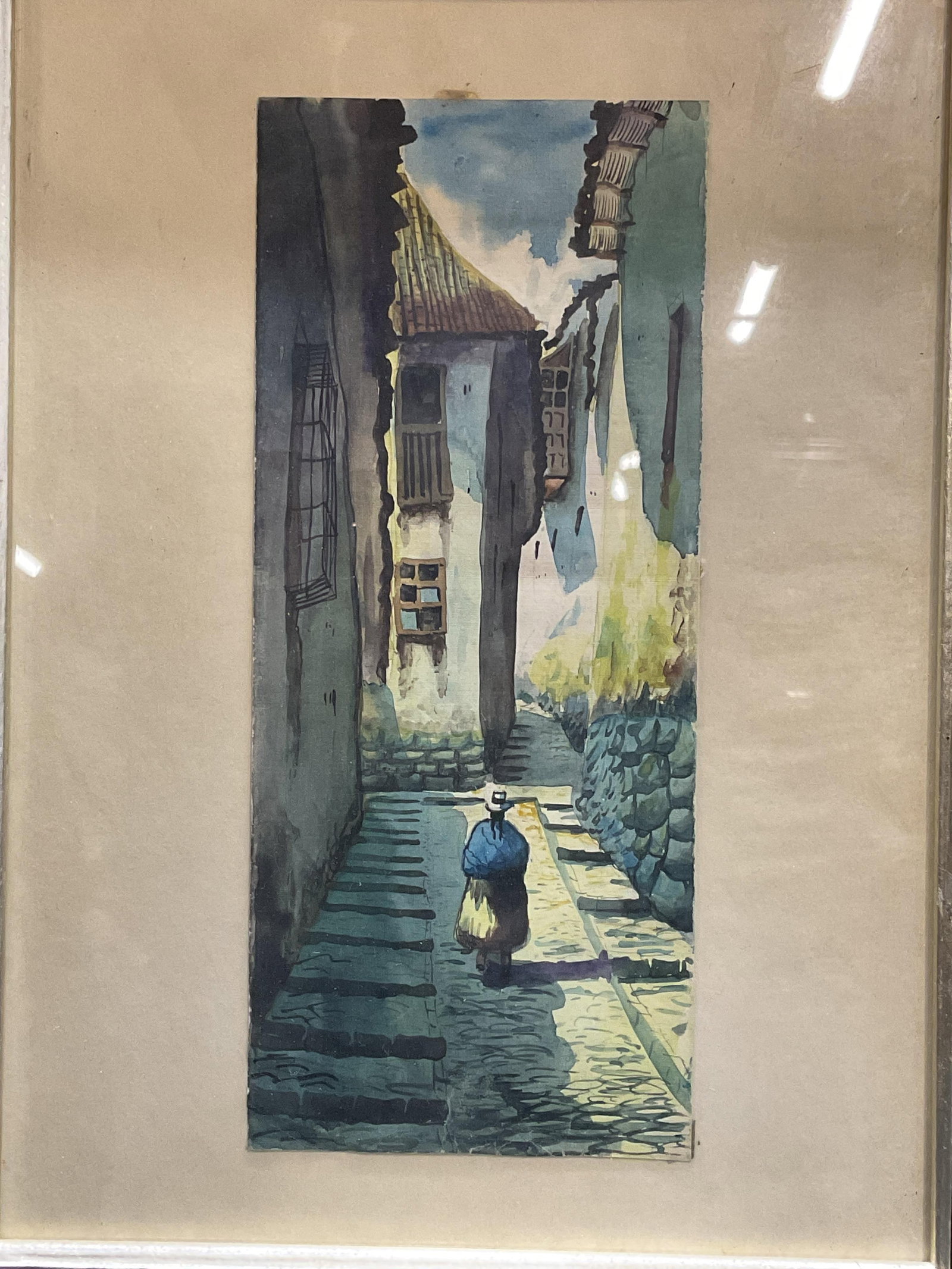 Framed Peruvian Street Scene Watercolor Painting: Framed watercolor painting on paper. Peruvian street scene with view of a woman walking and buildings. Wood frame, not examined out of frame. Frame measures approx 14.5 x 11.5 inches. Some wear includ