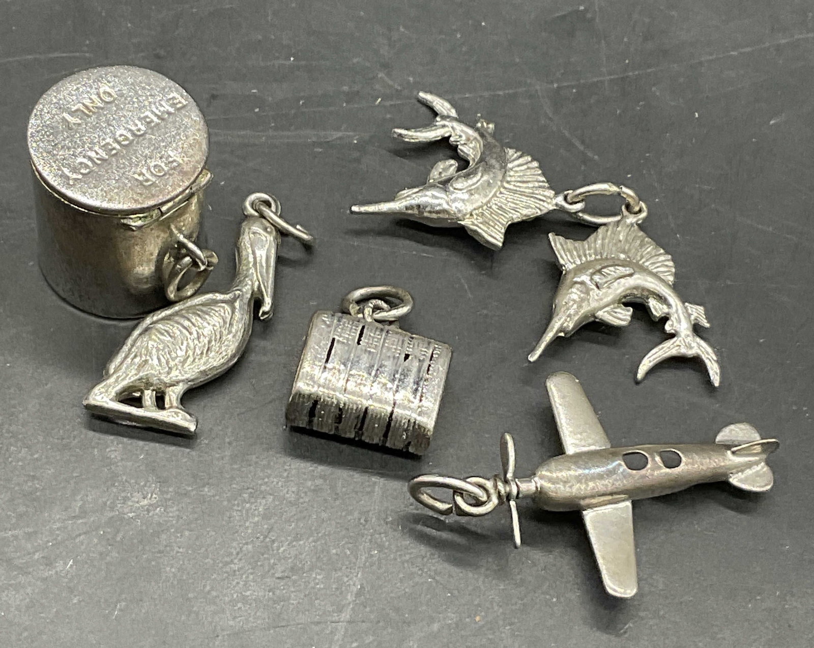 5 STERLING SILVER & Silver Tn Charms, Airplane +: Five sterling silver and silver tone (costume) charms. Includes fish, a plane, a bird, a suitcase, and a lidded cylindrical vessel. The cylindrical charm opens and reads For Emergency Only. The cylind