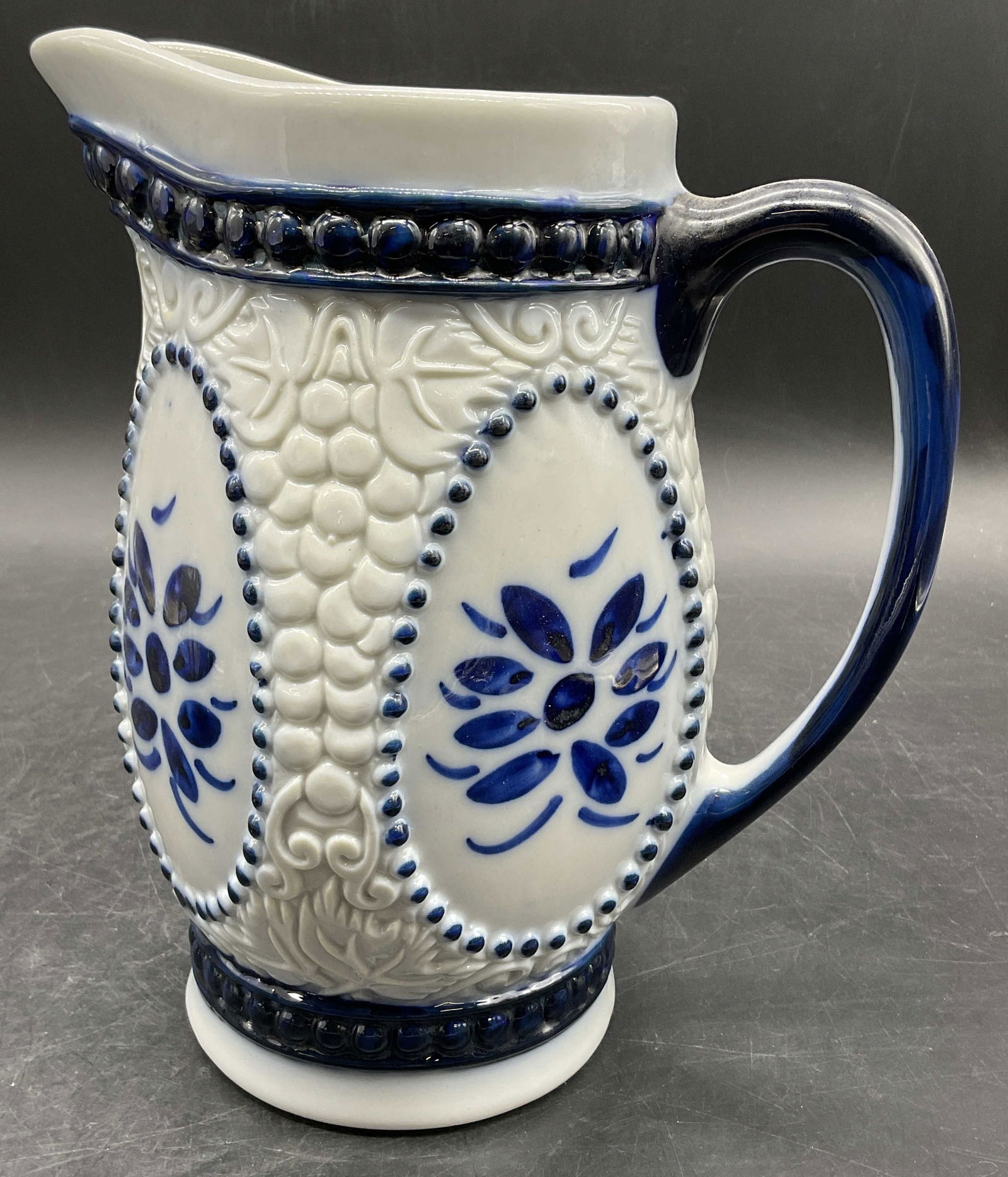 PORCELANA M. SIAO MG Hand Painted Pitcher, Bz: PORCELANA M. SIAO MG Hand Painted Porcelain Pitcher. Blue and white hues to the piece. Raised porcelain work to the sides. Underside reads PORCELANA, M. SIAO - MG. fone: 465- 1117, Brasil. Measures ap