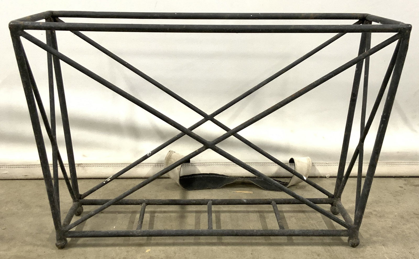 Vintage Iron Magazine Rack: Newspaper holder is black toned. Piece appears to be iron. Holder has x form structures. Piece has 4 feet. Piece measures approximately 18 inches wide 12 inches tall 6 inches deep. Newspaper holder, v
