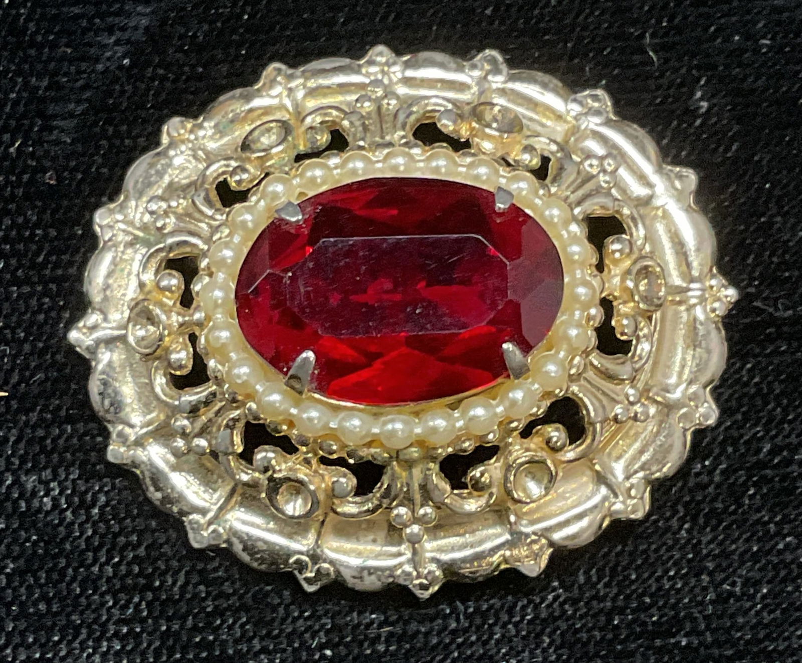 Vintage Coro Gold Tone Red Crystal Brooch: Vintage Coro gold tone brooch with faux pearl and red crystal. Signed on underside. Measures approx 1.5 x 1 inches. Some wear including scratching observed. Some crystal need replacement. Jewelry, est