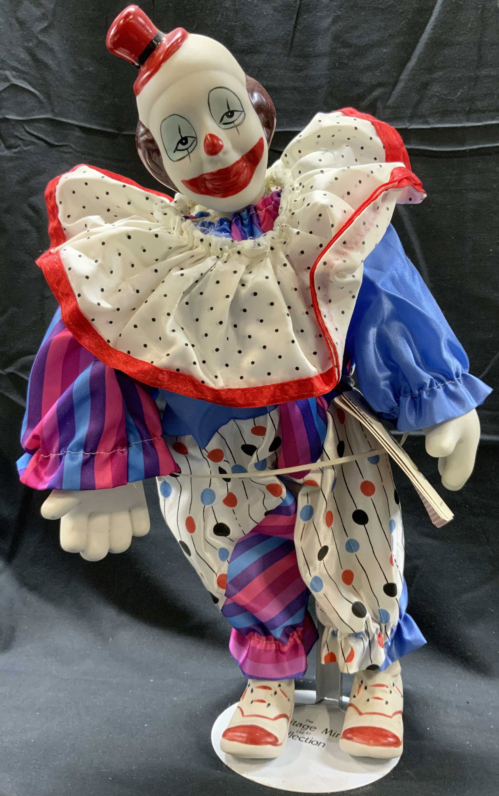 The Heritage Mint Collection Porcelain Clown Doll: The Heritage Mint Collection Porcelain Clown Doll Porcelain clown doll, clown is wearing a purple & blue striped outfit with a ruffled collar & a small red hat. Clown has playing cards attached on him