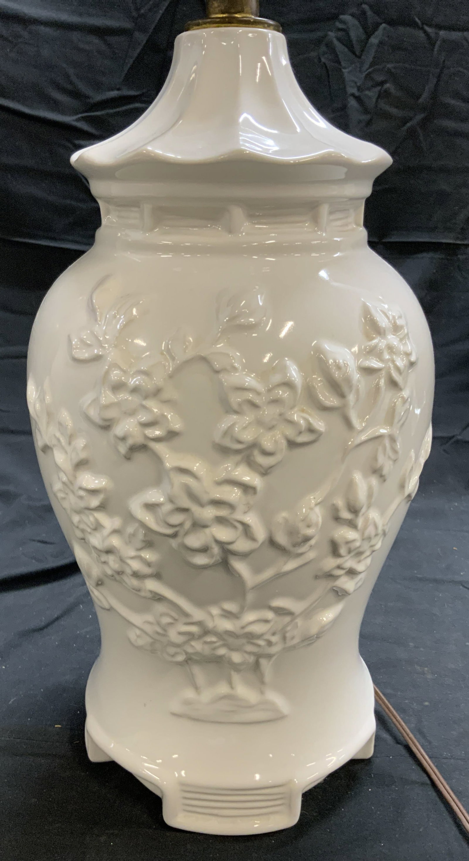White Porcelain Floral Detailed Table Lamp: Lamp is white toned & porcelain . Piece has floral & leaf detail. Lamp has gilt metal harp & finial. Piece measures approximately 26.5 inches tall 7 inches wide. Lamp, table lamp, side table lamp, end