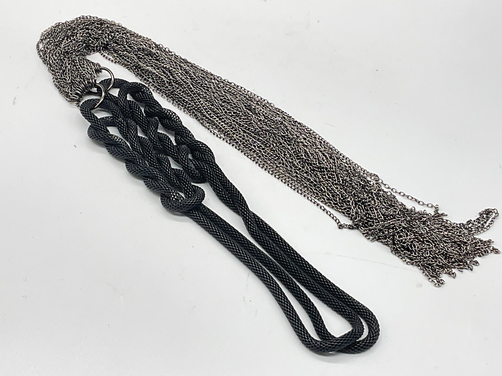 Multi Chain & Tubular Mesh Necklace: Multi Chain & Tubular Mesh Necklace. Crafted from black tubular knotted metal chain and silver tone metal chains. Length measured end to end approx 19 inches. Surface wear consistent with age, use, an