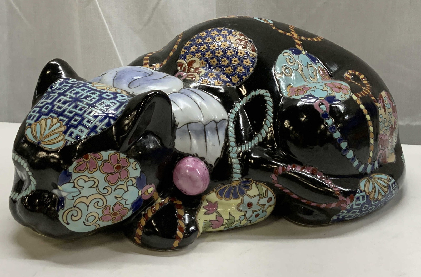 Black Floral Porcelain Cat Figural MACAU: Black Floral Porcelain Cat Figural MACAU Cat figural that has a floral pattern on body & appears to be sleeping. Cat has a black base color. Underside reads made in MACAU. Signed & marked. Surface wea