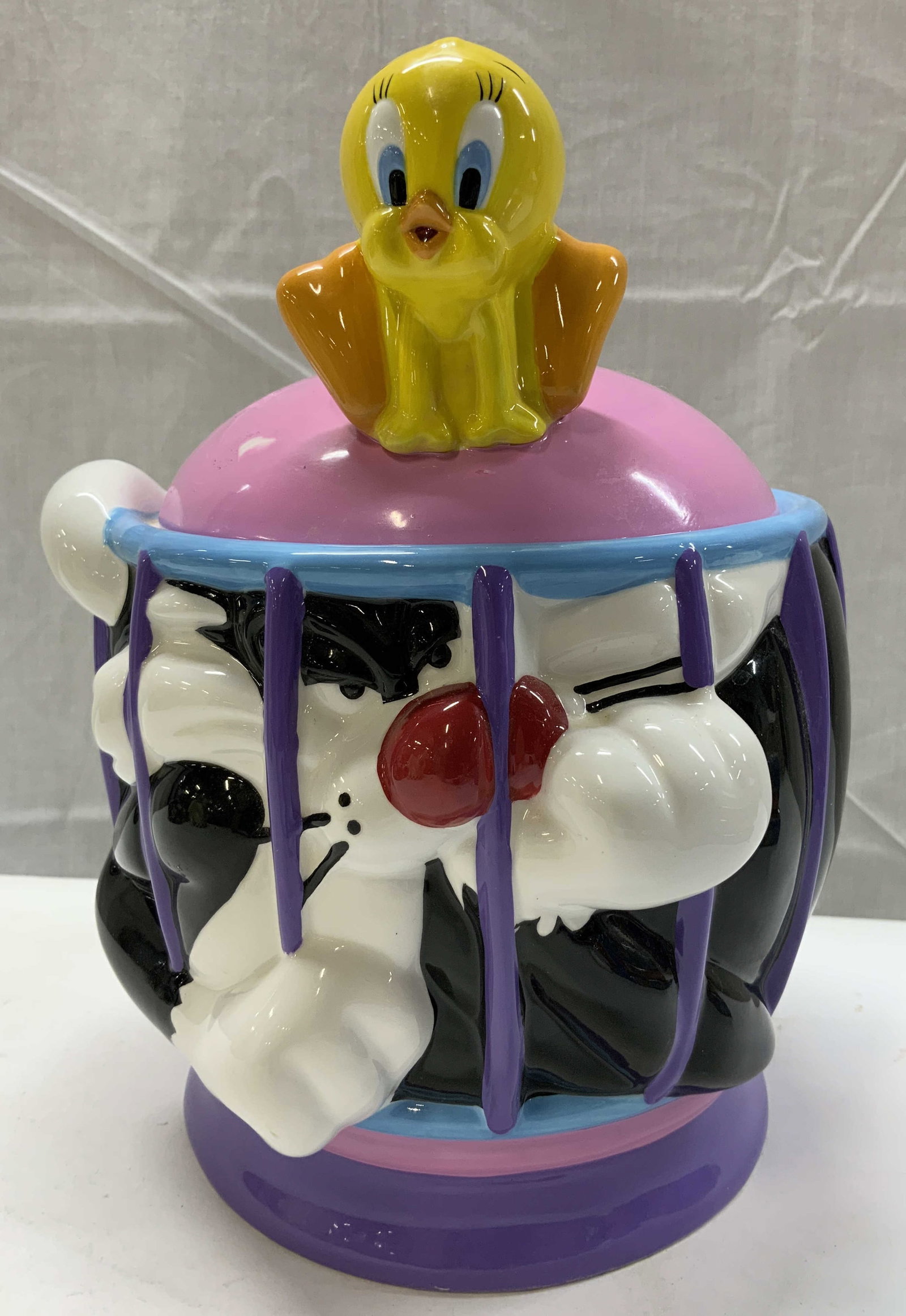 Vntg Looney Tunes Sylvester & Tweety Cookie Jar: Vntg Looney Tunes Sylvester & Tweety Cookie Jar Ceramic cookie jar in the shape of looney tunes characters, including Sylvester the cat & Tweety. Sylvester is caged in & Tweety is on a pink lid. Cooki