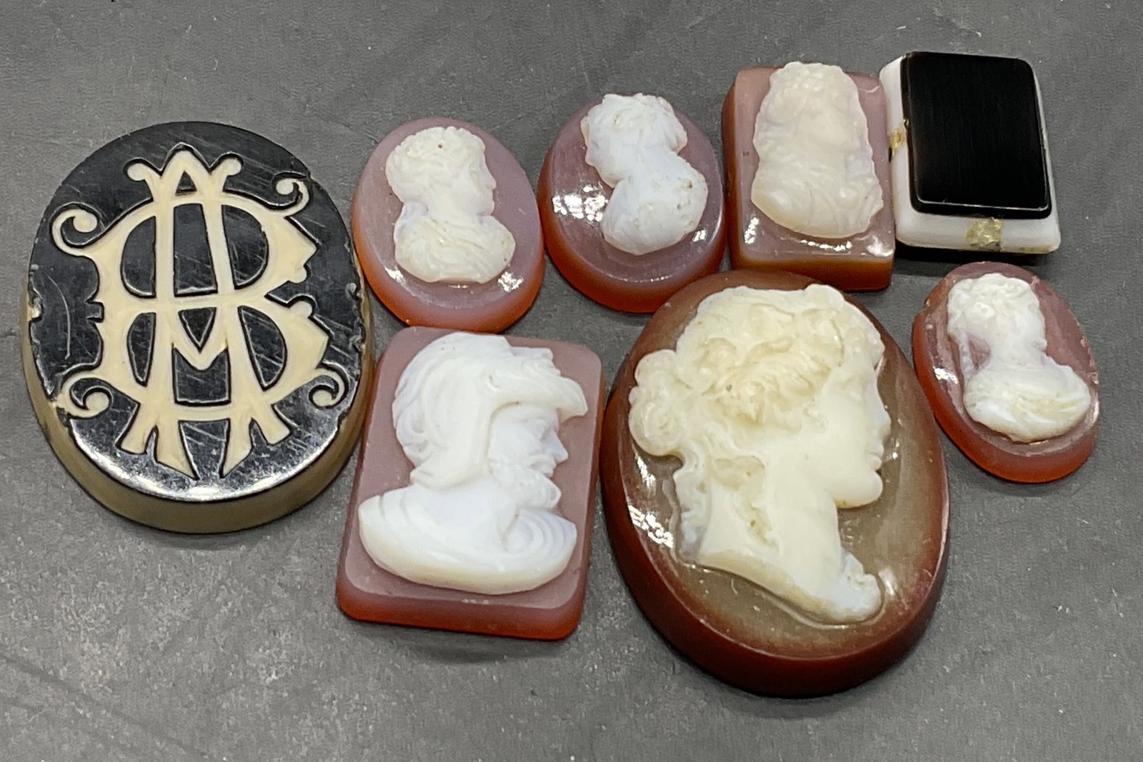 Lot 8 Vintage Male & Female Glass Cameos: Lot 8 Vintage Male & Female Glass Cameos. Pieces appear to be crafted from glass. The cameos feature white hued male or female busts. One piece features no figure. Oval or rectangular forms. Largest m