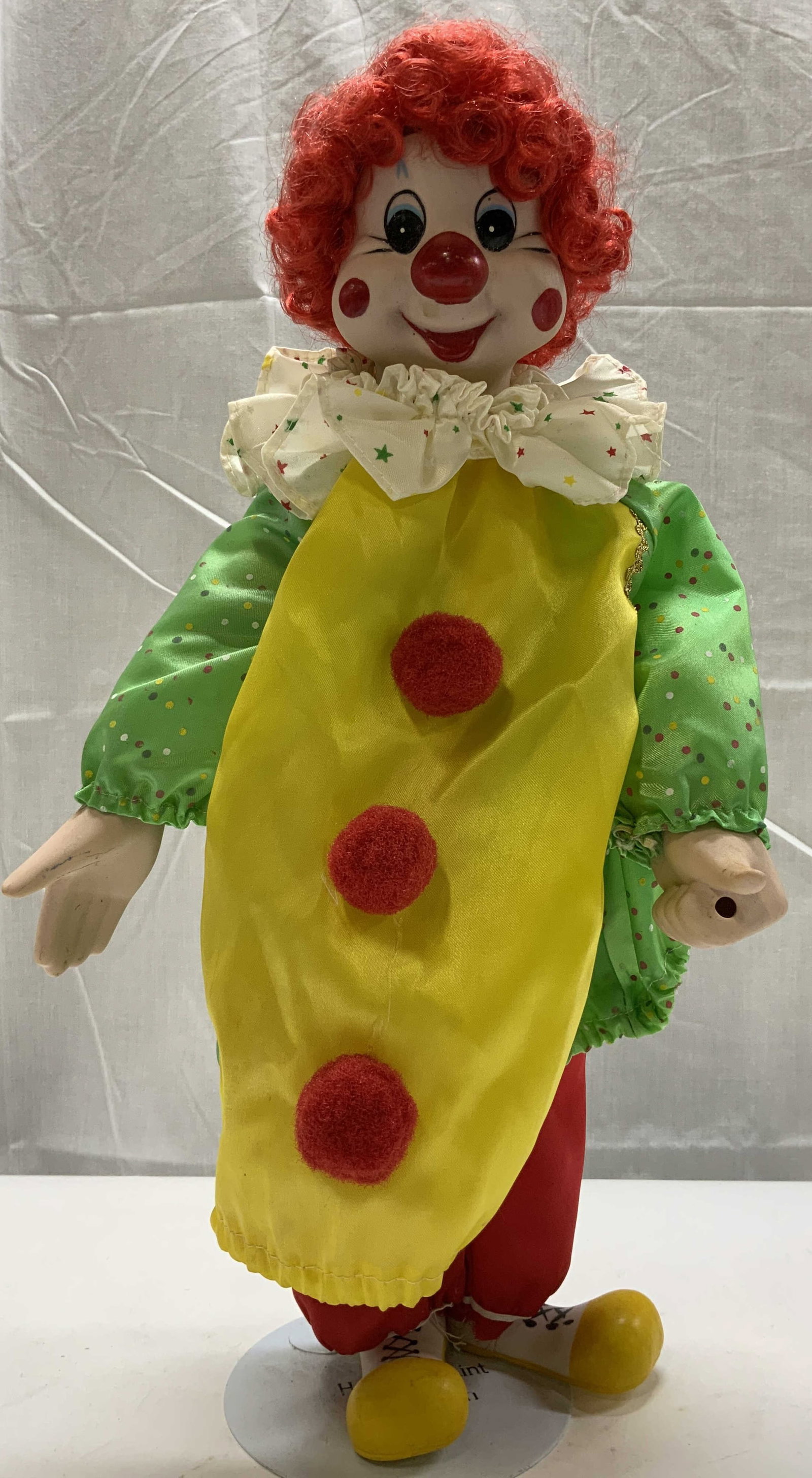 The Heritage Mint Collection Porcelain Clown Doll: The Heritage Mint Collection Porcelain Clown Doll Porcelain clown doll, clown is wearing a green & yellow top with red pom poms on his top. Clown has a white ruffled collar, yellow shoes & red hair. C