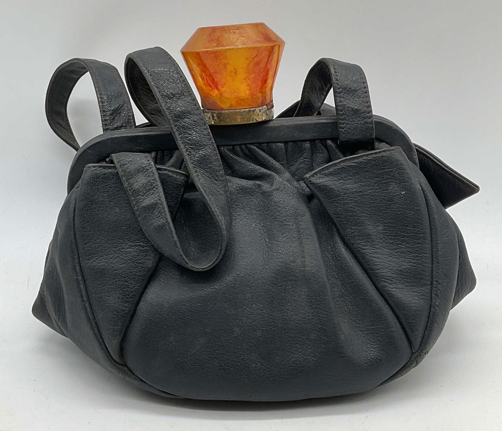 Vtg Jolles Saks Fifth Ave Black Leather Handbag: Vintage Jolles black leather handbag with orange lucite push clasp. Signed on label. Additional label reads Saks Fifth Avenue. Measures approx 8 x 5.5 x 4 inches. Wear to material including blemishes,