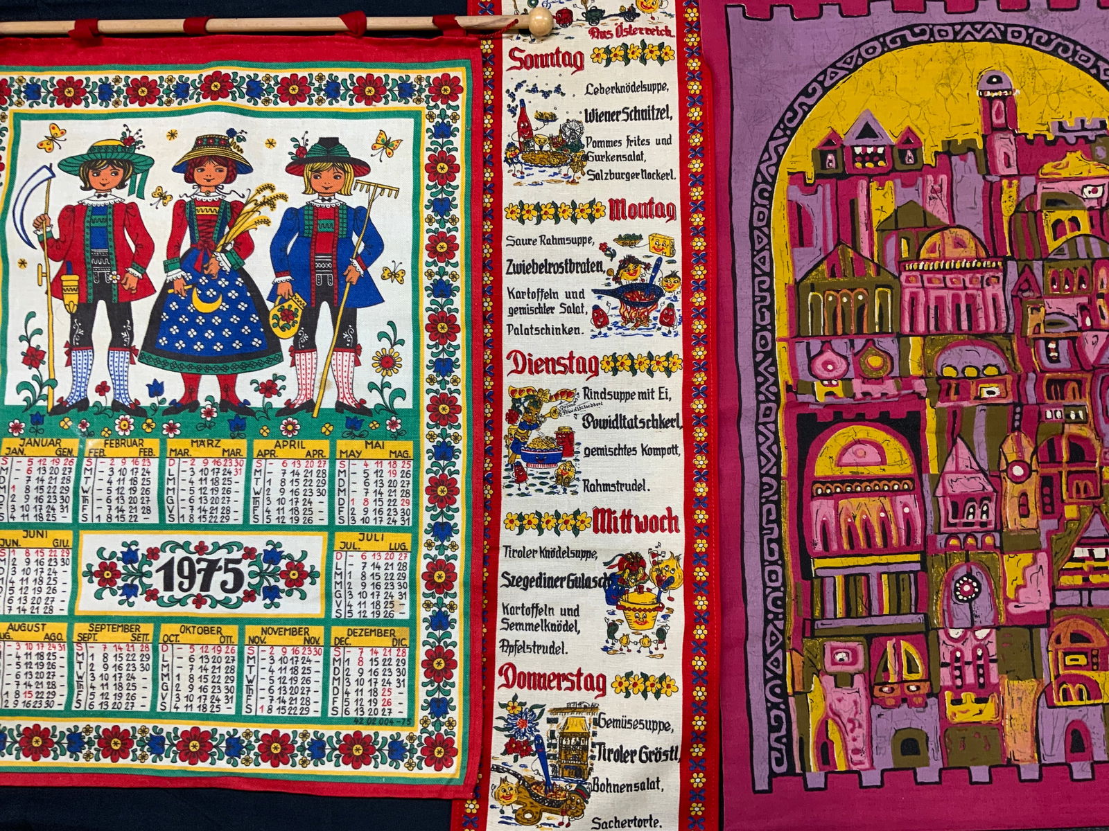 Lot 3 Folk Art Polish Cloth Wall Hangings: Three cloth wall hangings. 1975 calendar with folk art floral border and motif of children in traditional folk clothing. Months and days of the week in Polish. Long wall hanging with recipes and ingre