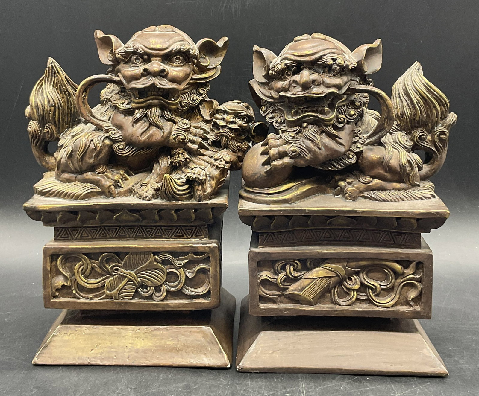 Pair BOMBAY 2000 Brown Fu Dog Bookends: Pair of BOMBAY C. 2000 Brown Resinous Fu Dog Bookends. Primarily brown with gold tone accents. Stickers to underside read C. 2000, BOMBAY. Similar in size measuring approx. 9H x 5W in. Writing, chippi