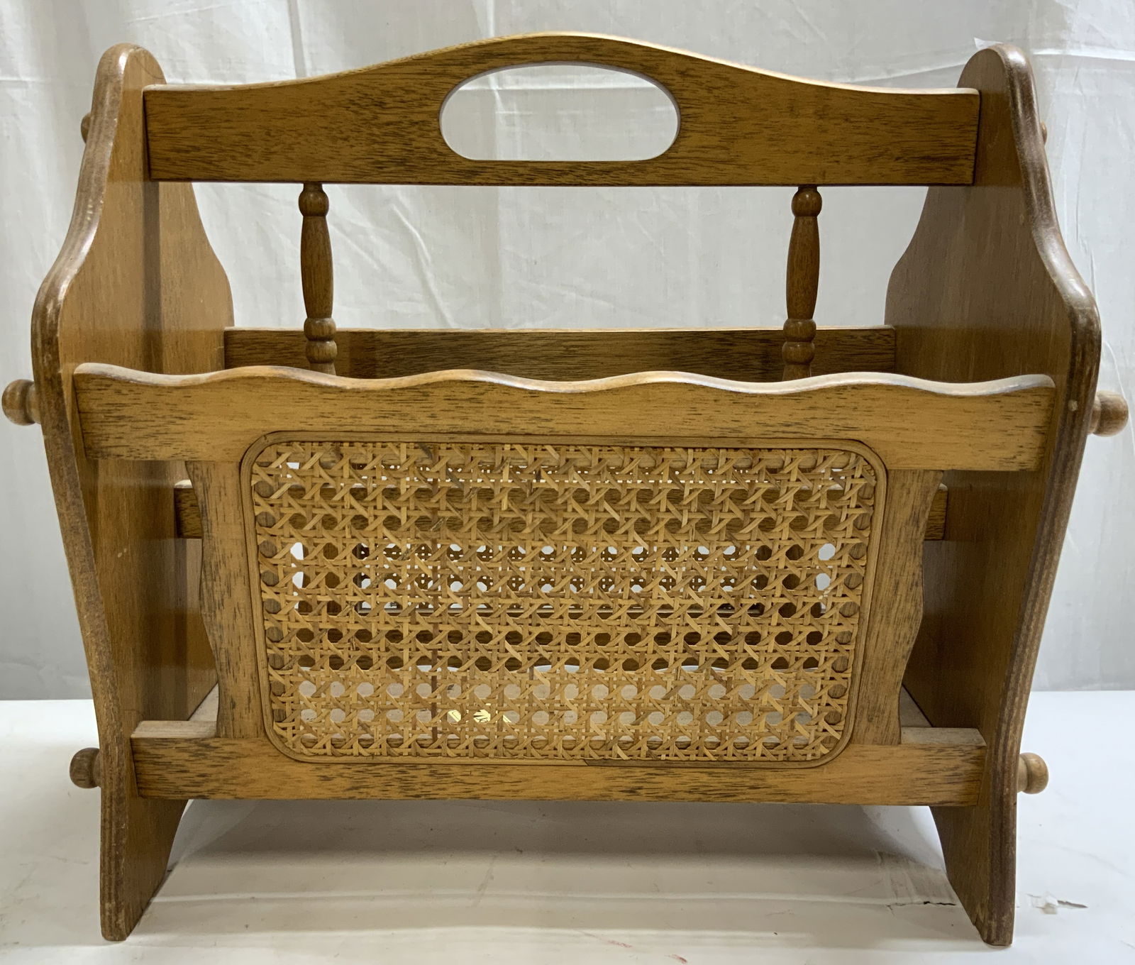 JAY Vntg Wood & Caned Magazine Rack: Tag on interior reads JAY. Magazine rack is tan toned and wooden. Piece has caned areas to sides. Center top of piece has handles. Magazine rack measures approximately 17.5 inches wide 15.5 inches tal