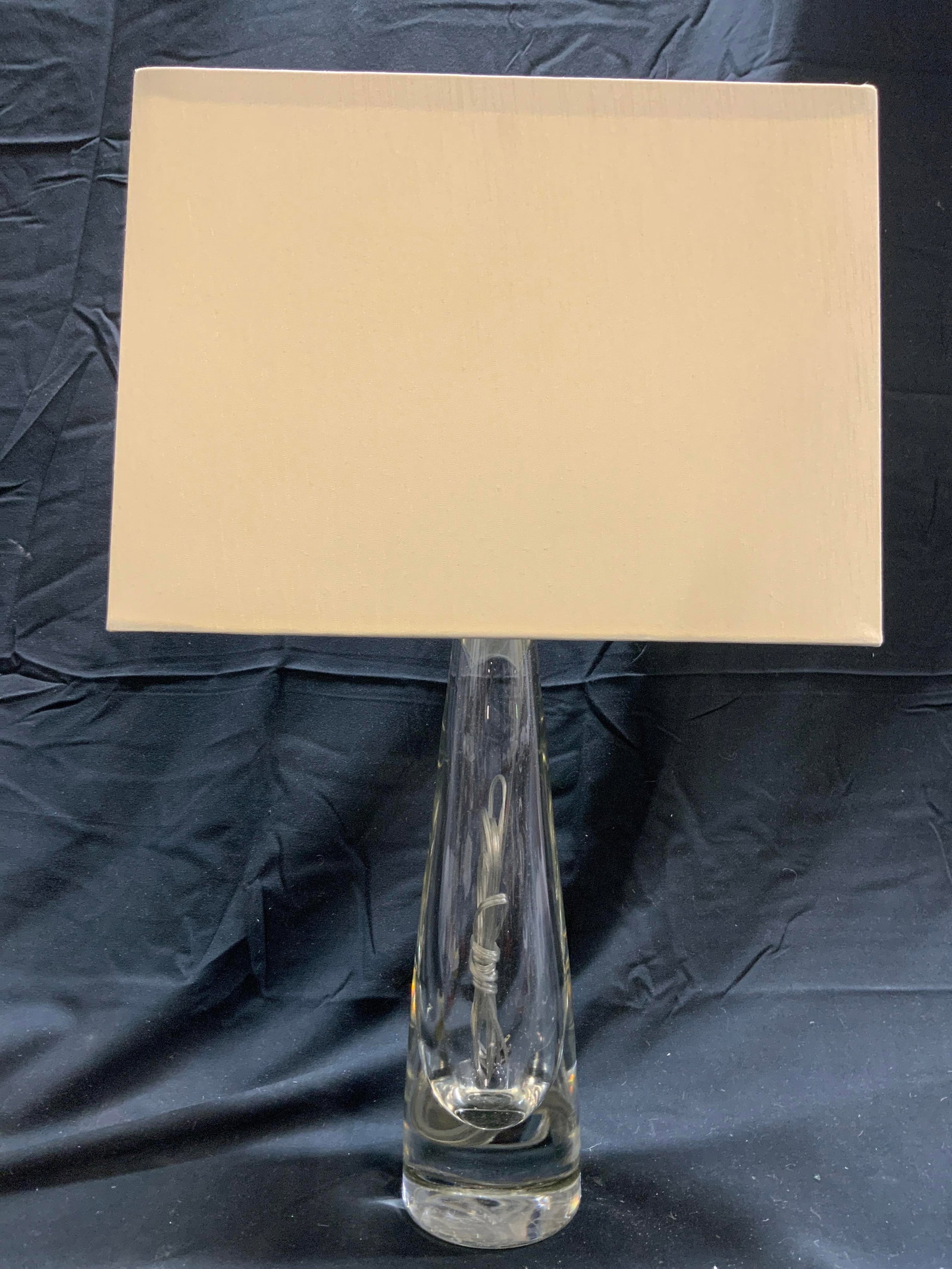 Art Glass Table Lamp W Shade: Lamp is table sized. Piece is glass. Lamp includes cream toned shade. Piece has thick walled floor. Lamp is possibly vintage. Piece measures approx 20.5 inches tall 3.5 inches wide at base. Shade (13 