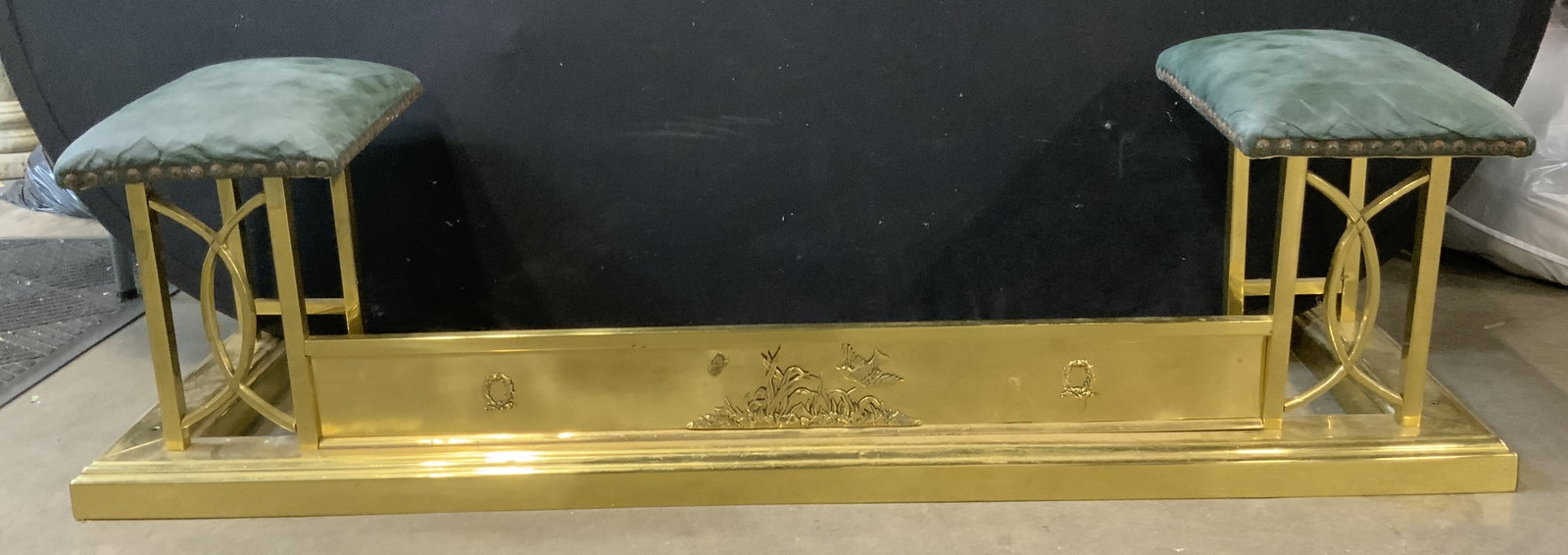 Vintage Brass Fireplace Bench W Nailhead Detail: Fireplace bench is vintage. Piece is gold toned and brass. Bench has sides upholstered with leather, possibly leatherette. Edges of upholstery have nailhead detail. Measures approximately 55.5 inches 