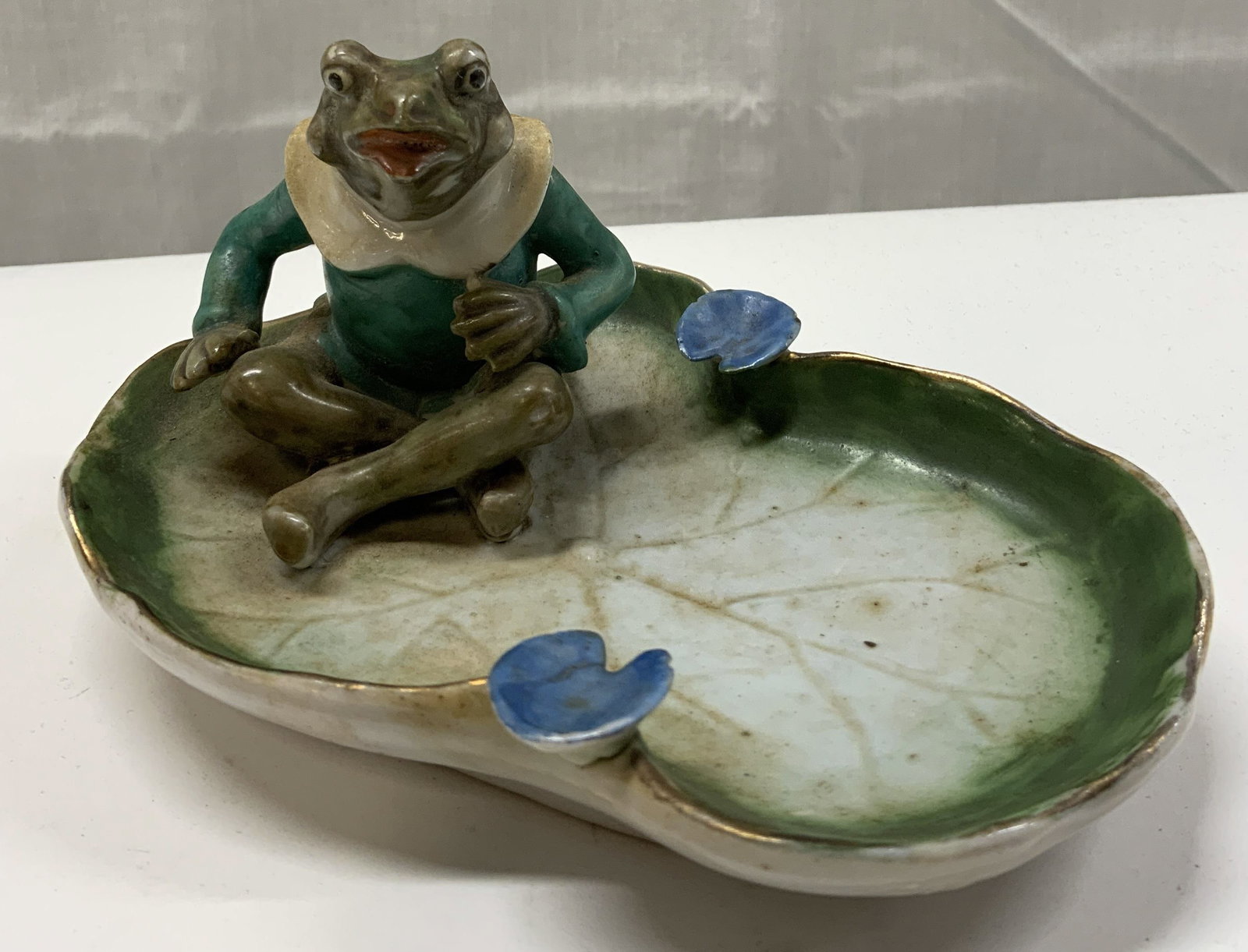 Vintage Frog Lily Pad Ashtray JAPAN: Vintage Frog Lily Pad Ashtray JAPAN Frog is sitting on a lily pad which serves as an ashtray. Underside reads, MADE IN OCCUPIED JAPAN. Porcelain ashtray has a gold trim. Marked & signed. Surface wear 