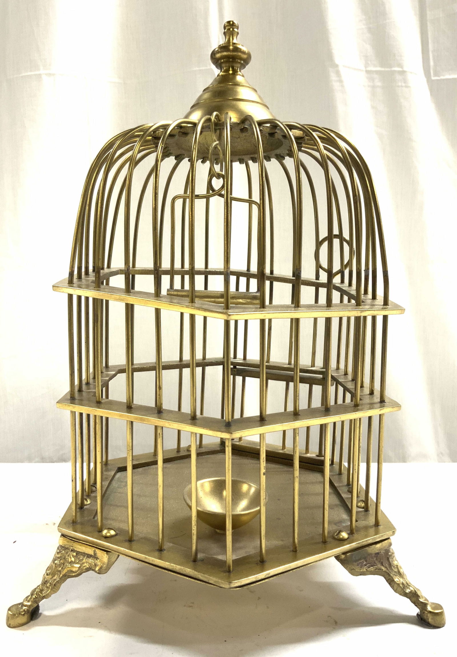 ETHAN ALLEN Footed Brass Birdcage: Tag on Underside reads ETHAN ALLEN. Birdcage is gold toned and brass. Interior has bowl & hanging perch. Piece has door. Cage has 3 feet. Base has hexagonal form. Top of cage resembles finial. Bird ca