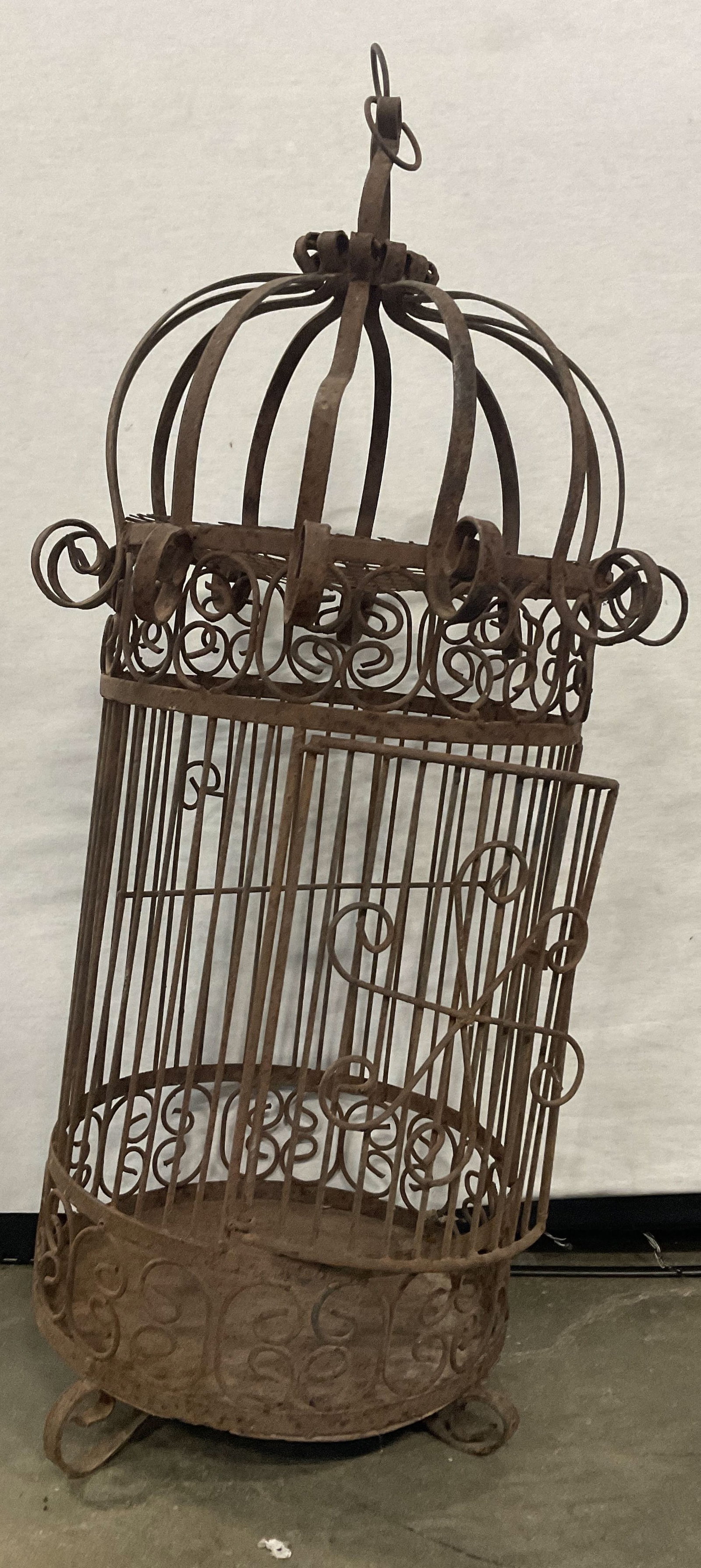 Vintage Iron Scrolled Metalwork Birdcage: Vintage Iron Scrolled Metalwork Birdcage. Door to obverse opens. Measures approx. 27.5H x 14W in. Denting and warping to the iron, wobble to piece. Discoloration and surface wear present. Hardware to 