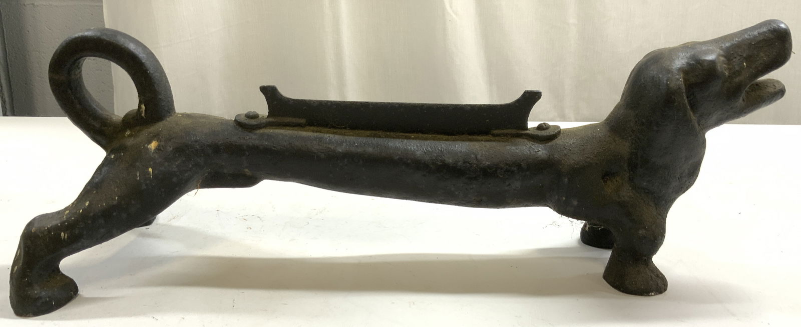 Antq Cast Iron Dachshund Boot Scraper Extra Long: Boot scraper is antique. Piece is cast iron. Boot scraper is in the form of a standing dachshund dog with mouth open. Piece is black toned. Boot scraper measures approximately 22 inches long 8 inches
