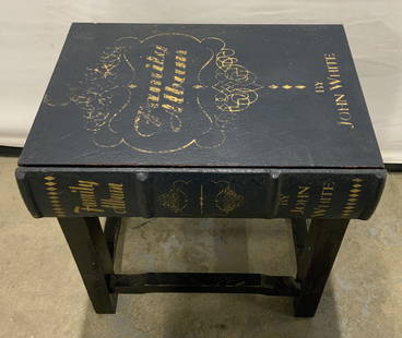 Family Album by John White Wooden Side Table: Family Album by John White Wooden Side TableWooden side table that has a book cover look as the tabletop. It has gold embossed lettering. Family Album by John White. Tabletop has a navy color & 4 blac