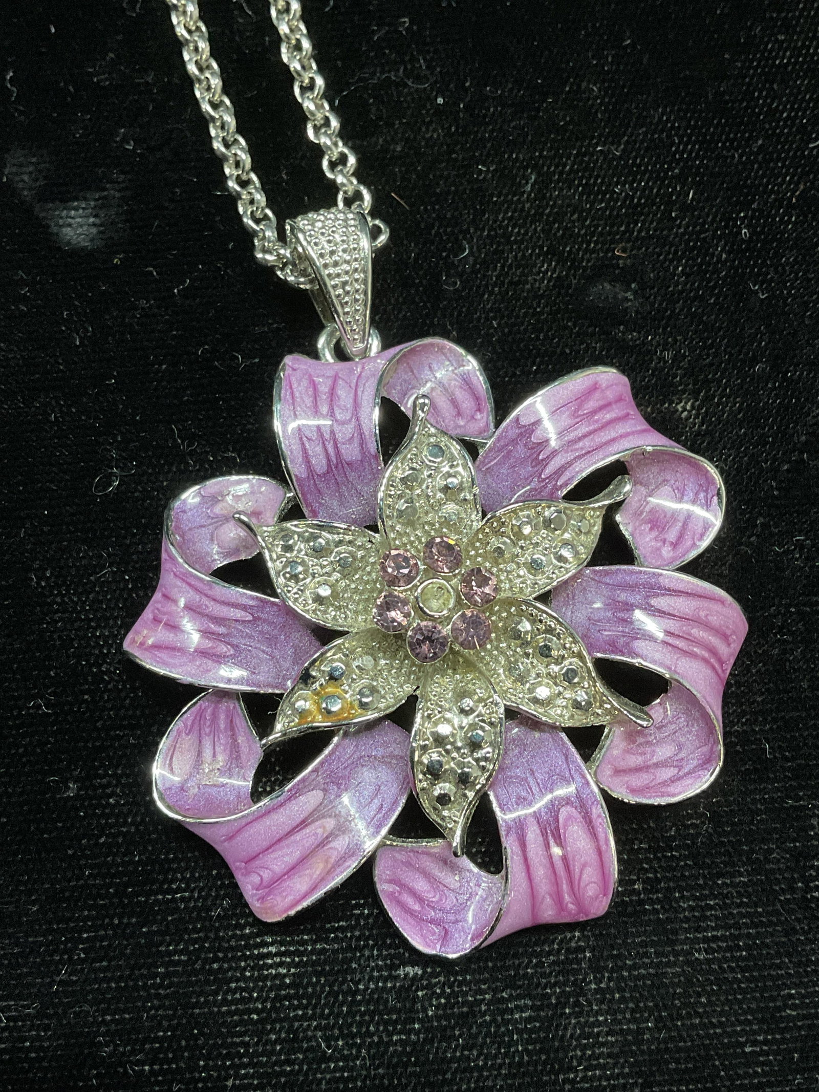 Purple Crystal Flower Pendant Necklace: Silver tone chain pendant necklace. Purple enamel and crystal flower motif pendant. Pendant measures approx 2 inches wide. Drop length approx 8.75 inches. Some wear including scratching. Jewelry, esta