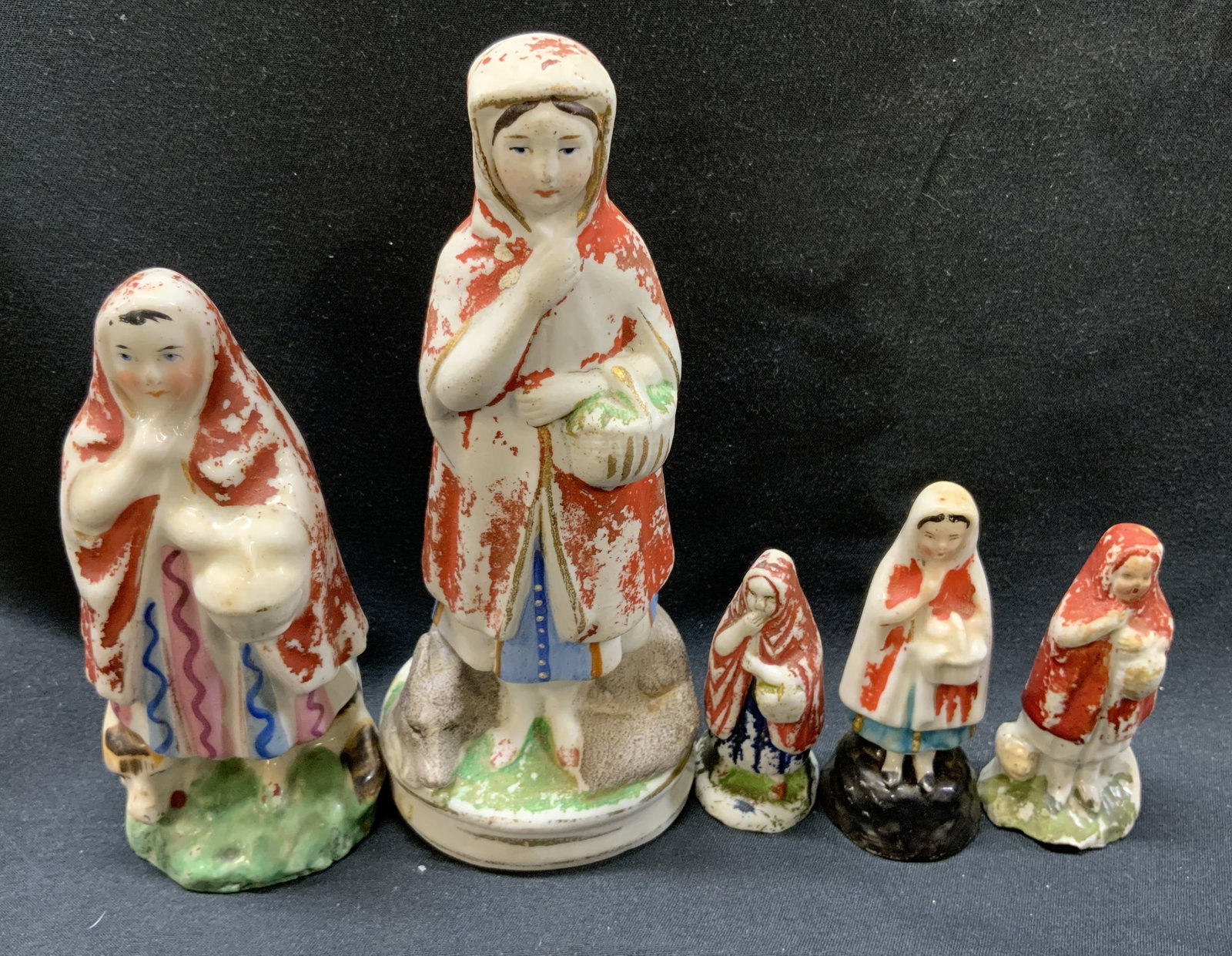 Group Lot Antique Little Red Riding Hood Figurals: Group lot Antique Little Red Riding Hood Figurals 5 porcelain figural, they all have red hooded capes with blue, white or pink dresses. They are each holding a white basket. Including a few figural ha