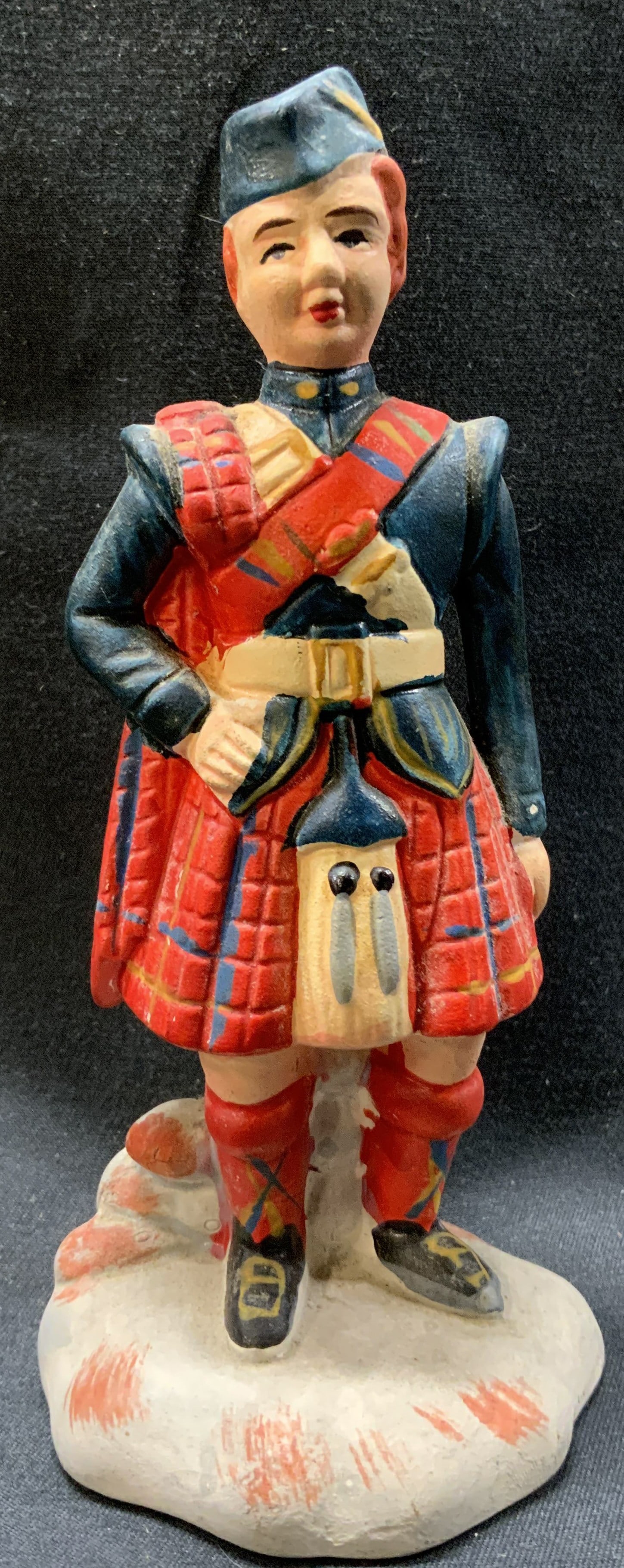 Vintage Daysun Ceramic Scottish Man Figurine: Vintage Daysun Ceramic Scottish Man Figurine. Scottish man wearing a traditional Scottish kilt & uniform. Has red & blue colors. Has one arm on waist and the other on his side. Appears to be standing 