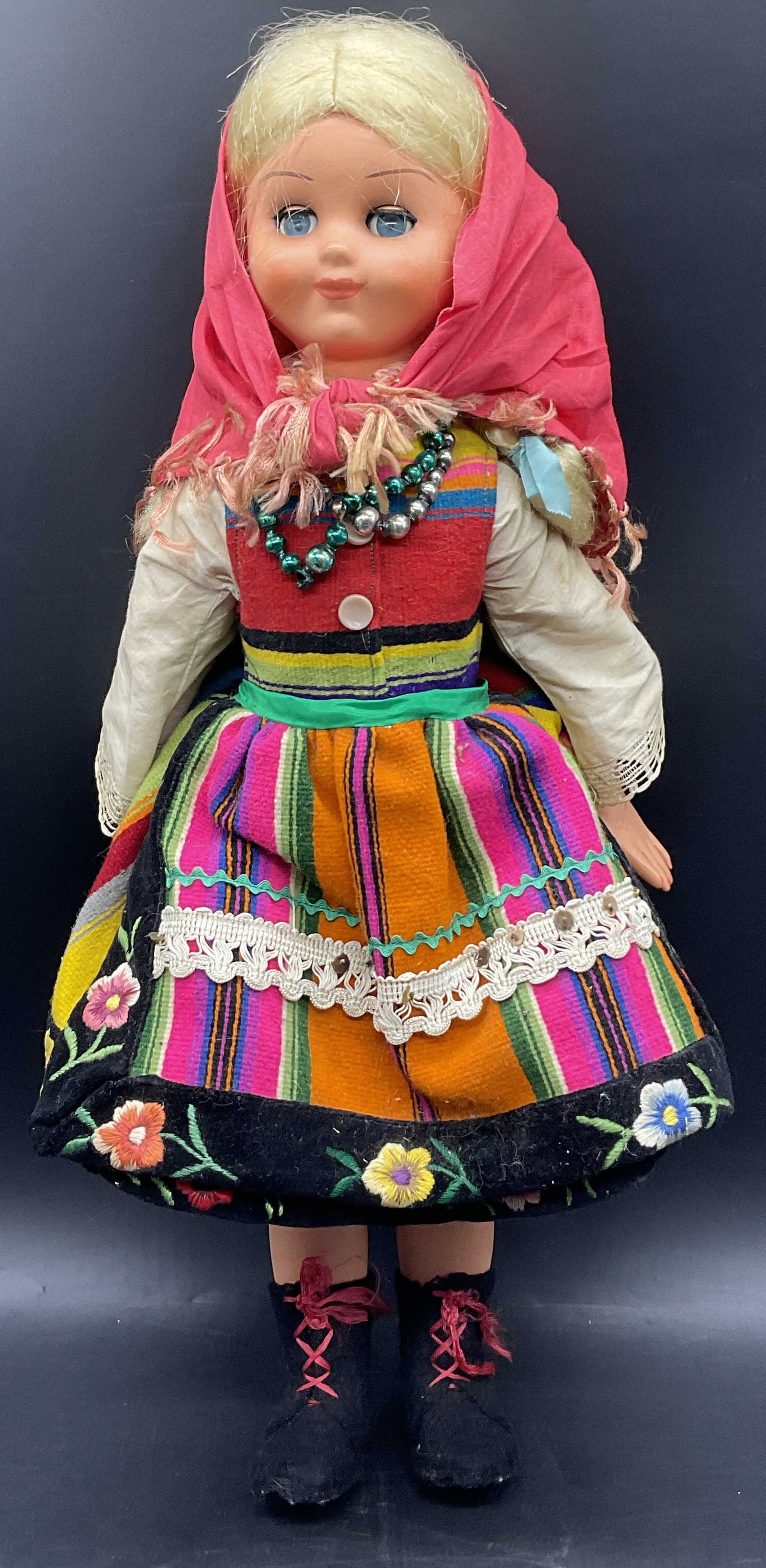 Vintage Folk Doll W/ Articulated Eyes: Vintage Folk Doll With Articulated Eyes. The doll is composite and wears colorful fabric clothing. Her eyes open and close. Measures approx. 20H x 8W in. Discoloration, surface wear, and losses to mat