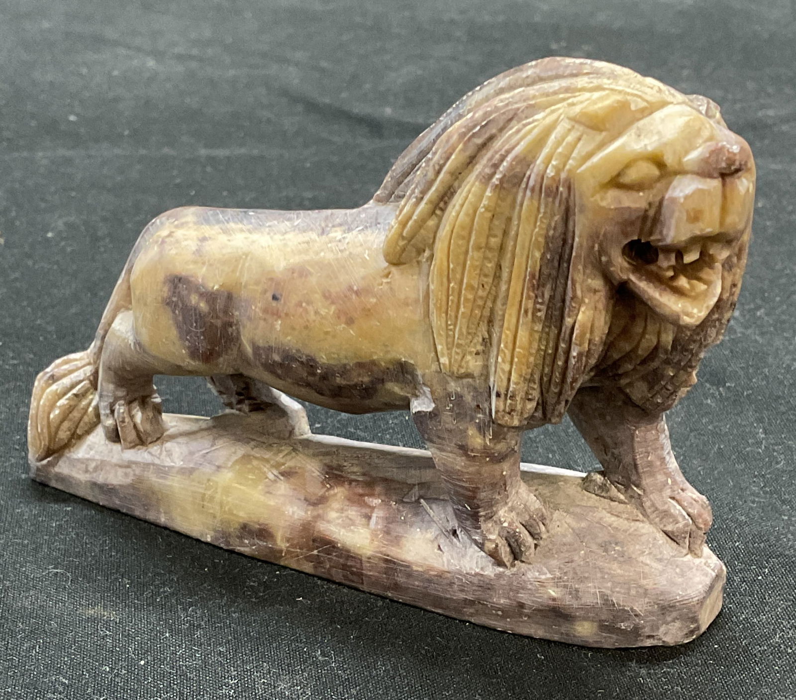 Hand Carved Soapstone Lion Figural: Hand carved soapstone lion figural. Measures approx 4 x 1 x 2.75 inches. Some scratching observed. Lion, lion figural, stone lion, soapstone lion, decorative arts, home decor, home accessories, table