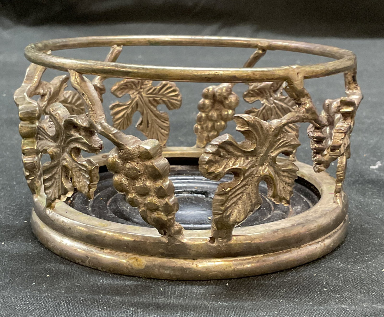 Vtg Silver Plated Grapevine Wine Bottle Coaster: Vintage silver plated grapevine motif wine bottle coaster. Piece has weight. Measures approx 4.25 x 2.25 inches. Wear including scratching and patina. Wine bottle coaster, bottle coaster, silver plate