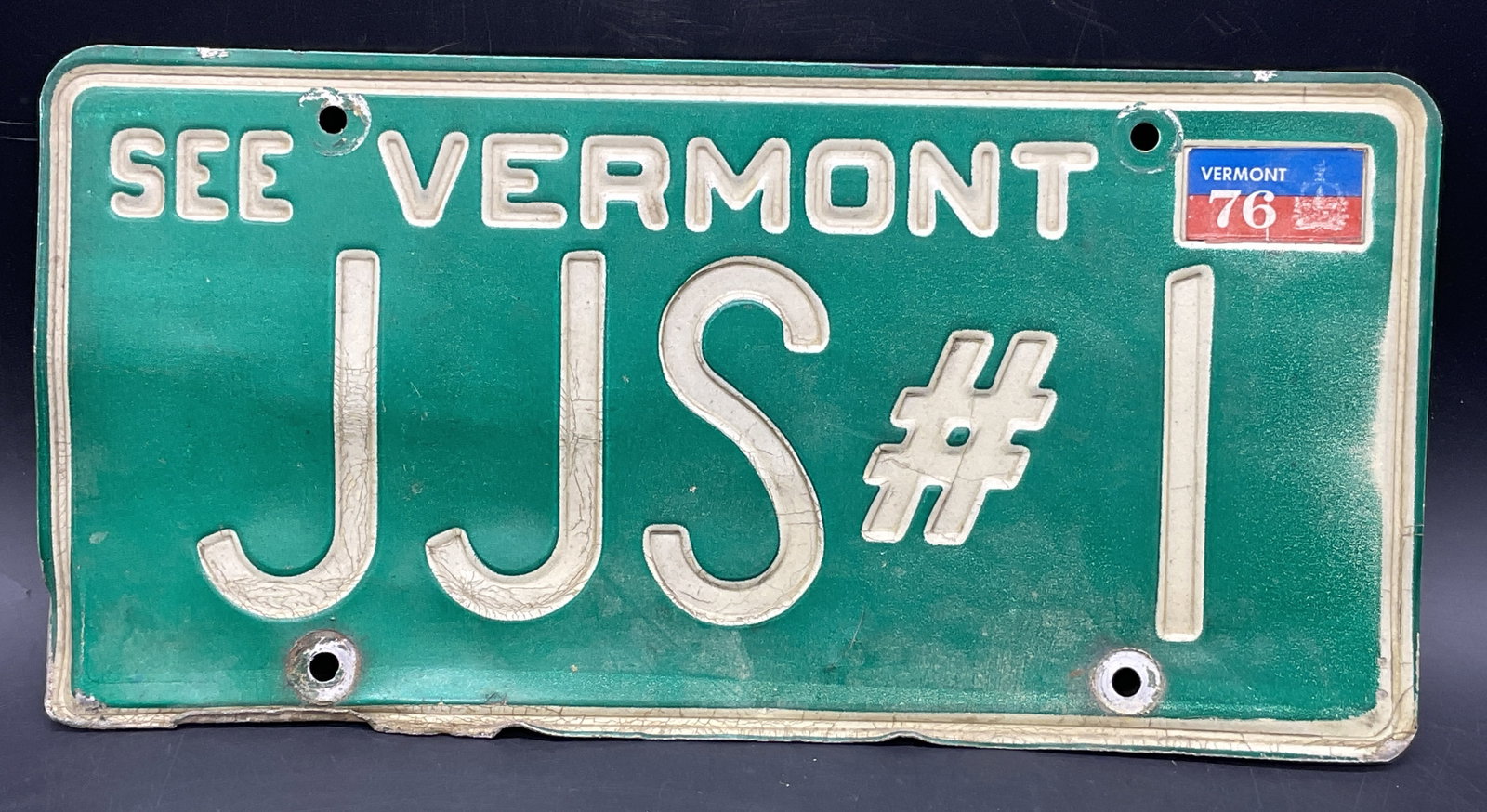 Vintage VERMONT JJS#1 Green Metal License Plate: Vintage VERMONT JJS#1 Green Metal License Plate. Rectangular form. Upper right hand corner reads VERMONT 76. Measures approx. 6L x 12W in. Losses, denting, and surface wear present. home decor, home a