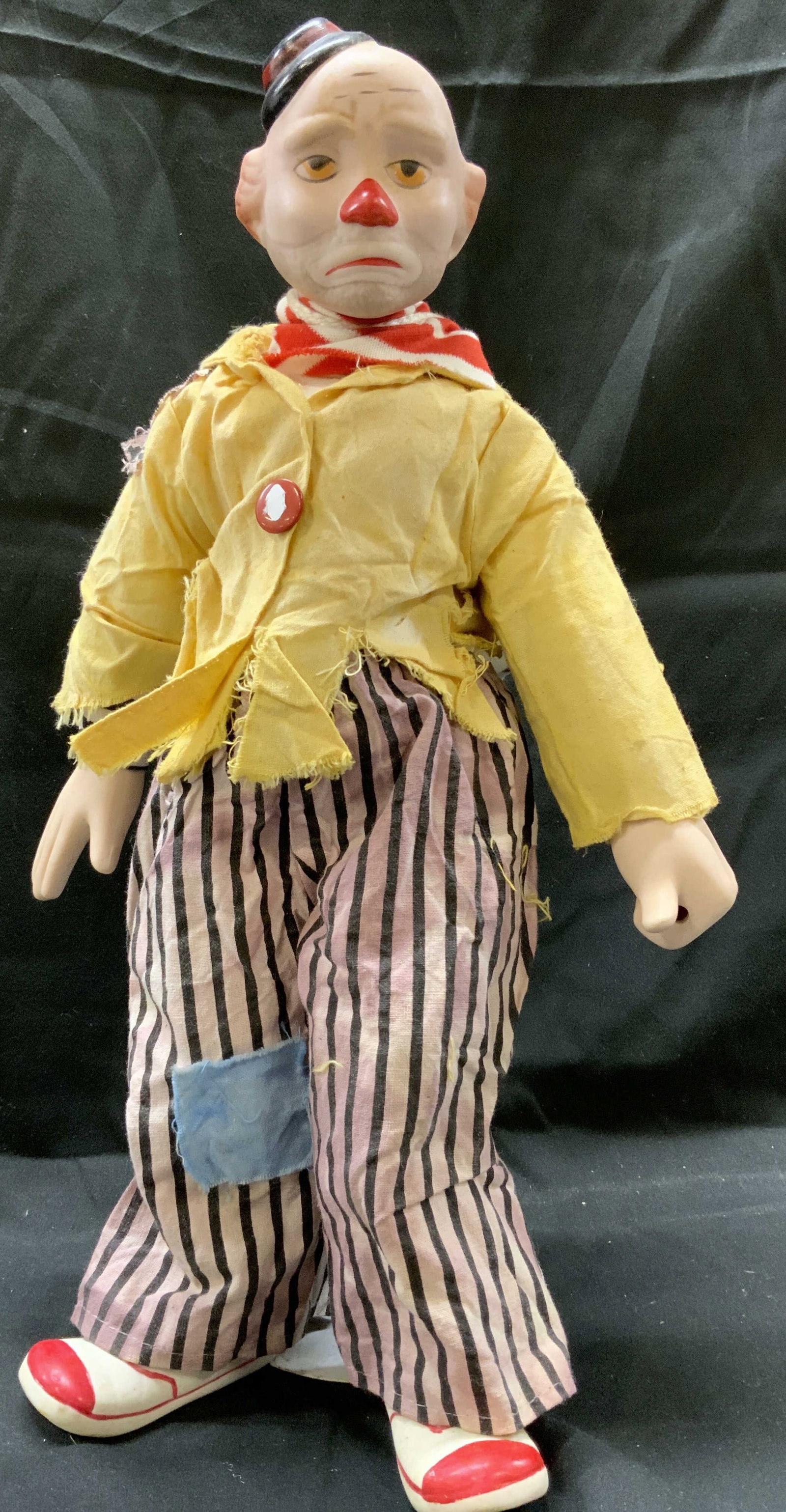The Heritage Mint Collection Porcelain Clown Doll: The Heritage Mint Collection Porcelain Clown Doll Porcelain clown doll, clown is wearing a yellow top with striped pants. He is carrying a blanket & pillow on his back. Clown has a metal stand. Marked