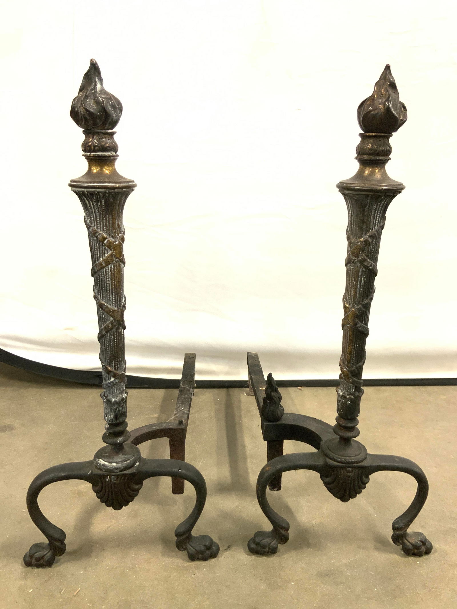 Antique Wrought Iron Torch Andirons: Lot includes 2 andirons. Each appear to be antique possibly vintage. Andirons have torch forms. Each have 2 s curve feet. Andirons measure approximately 18.5 inches deep 20.5 inches tall 8 inches wide