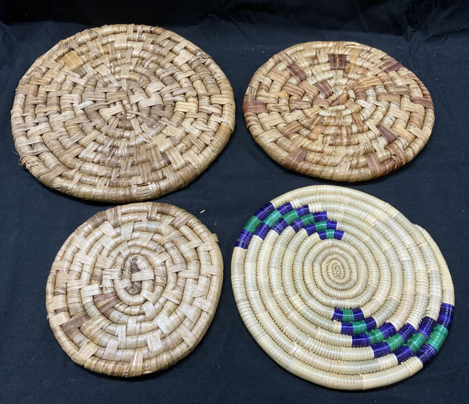 Lot 4 Vintage Circular Rattan Trivets: Lot includes 4 trivets. Each appears to be rattan. Trivets have circular forms. Each piece has various Tan tones. Largest trivet measures approximately 9.5 inches diameter. Trivets, rattan trivets, vi