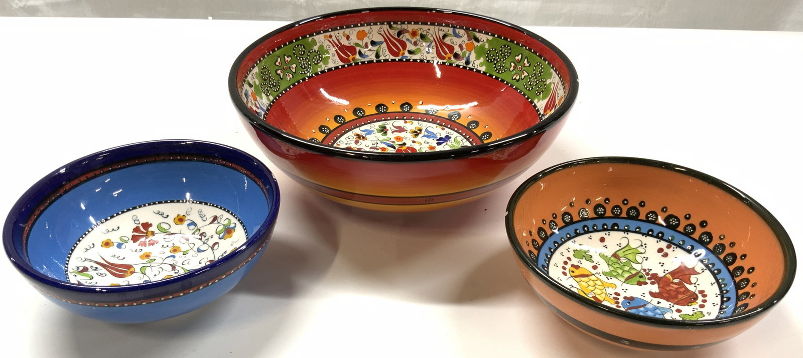 NIMET Lot 3 Hand Painted Turkish Bowls: Underside of bowl is marked NIMET. Lot includes 1 large bowl and 2 smaller bowls. Each are ceramic and appear to be hand painted with multi toned floral and leaf detail. Each bow has black toned rims 