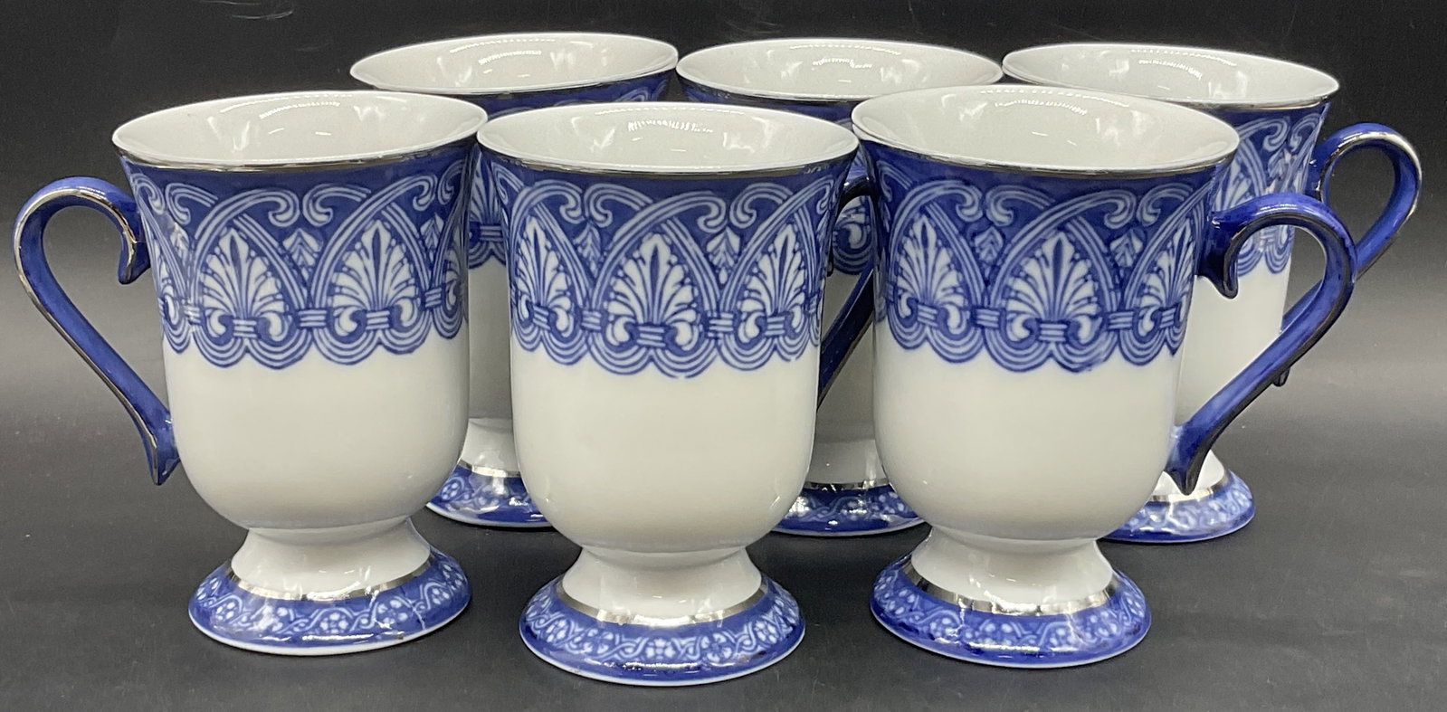 Set 6 BOMBAY Blue & White Porcelain Mugs: Set of 6 BOMBAY Blue & White Porcelain Mugs. Measures approx. 4.5H x 3W in. Width measured at mouth of cup. Underside marked BOMBAY. Surface wear consistent with age, use, and exposure. Pitting presen