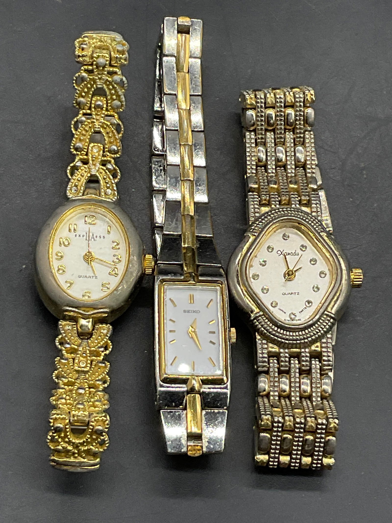 3 LA EXPRESS, SEIKO, & XANADU Vintage Wristwatches: A lot of three vintage metal wristwatches. Crafted from silver and gold toned metal. Brands include LA EXPRESS, SEIKO, & XANADU. Two have clasp closures, one has a stretch band. The length of the SEIK