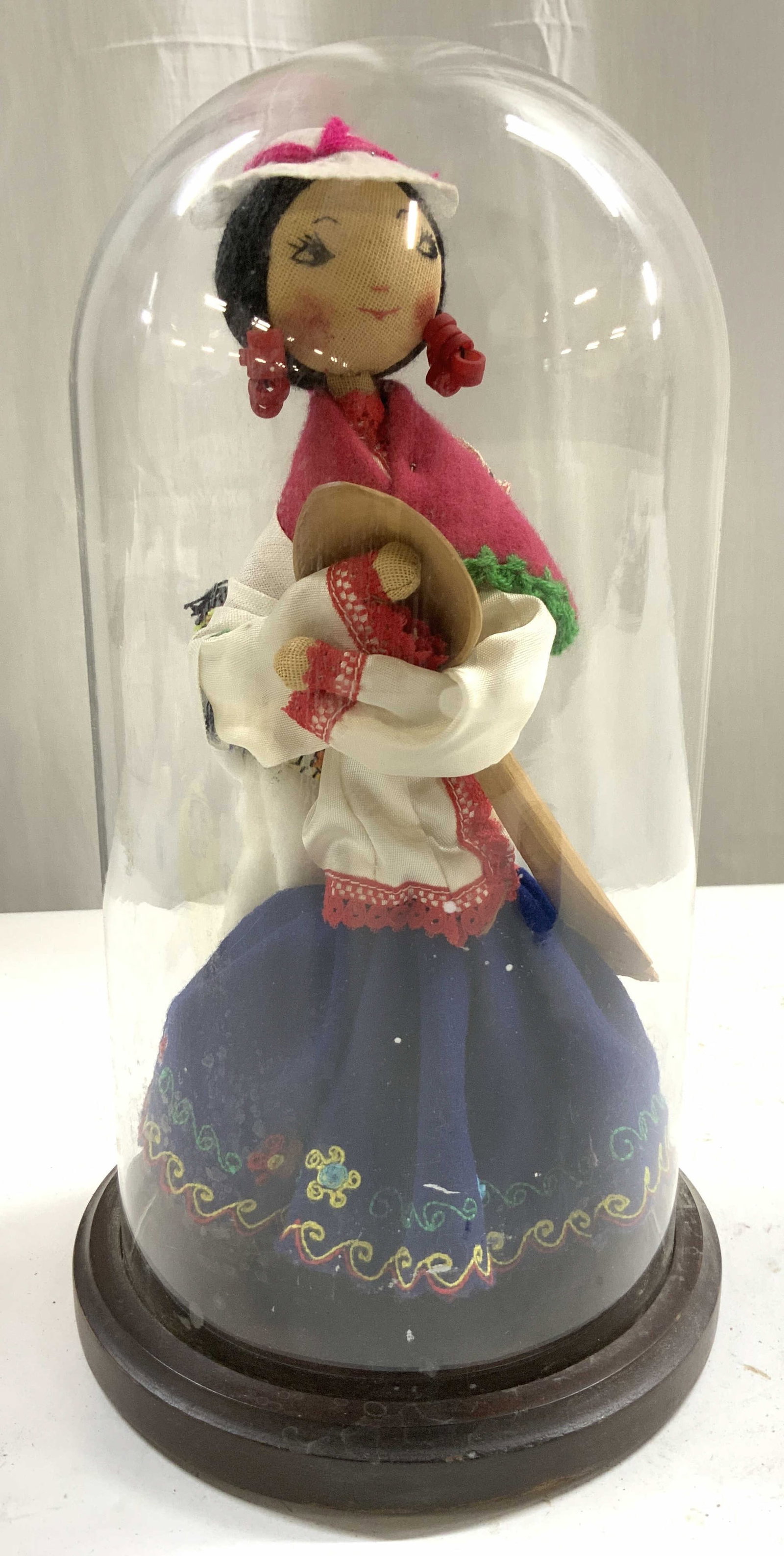 Vintage Cloth Polish Dancer Doll In Glass Cloche: Doll is vintage. Piece depicts female polish dancer figure with blue toned skirt and white toned hat. Doll is sits on brown toned wooden base & has glass dome. Doll with dome measures approximately 11
